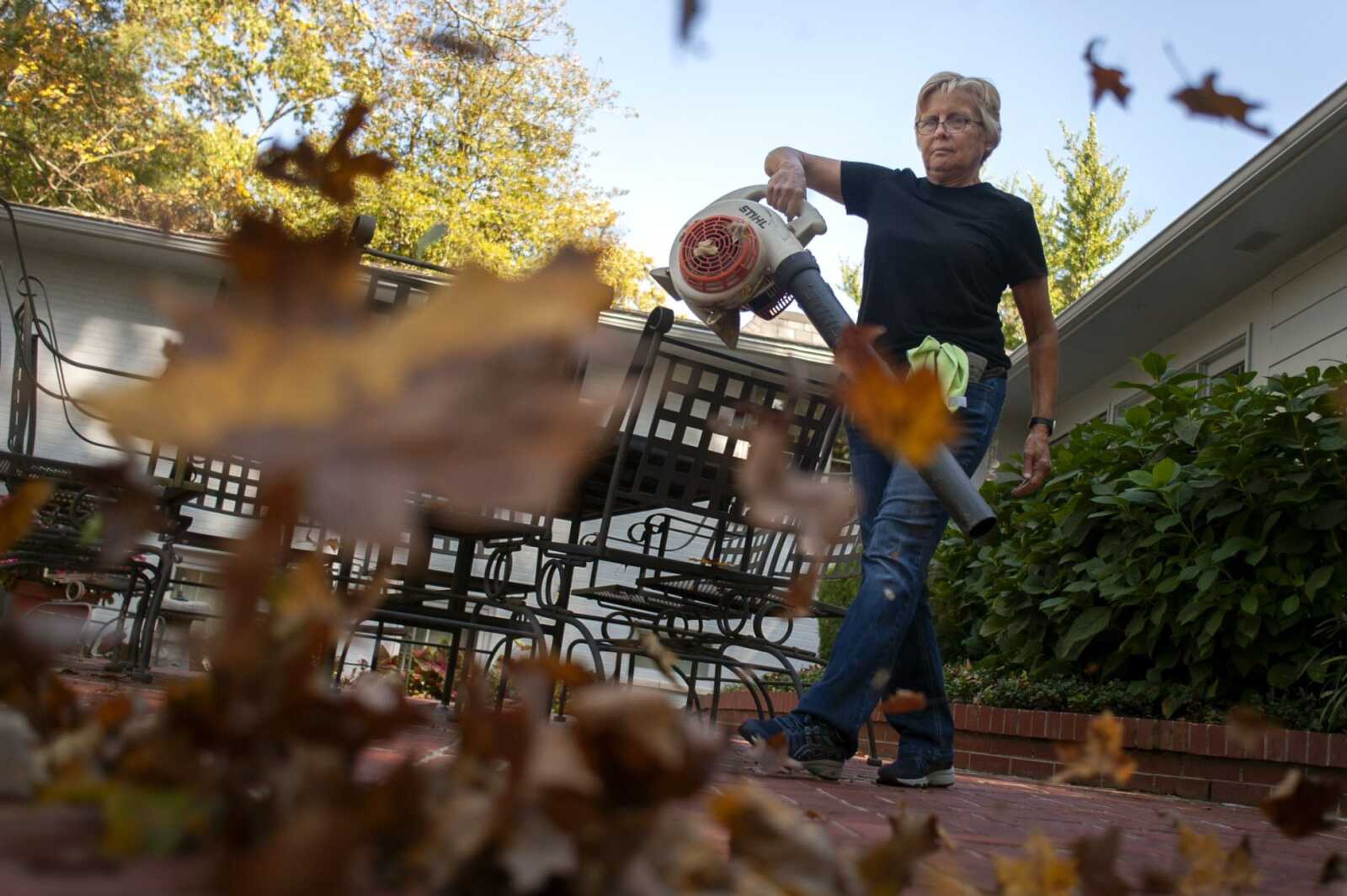 NormaJean Lauck of Apple Creek, Missouri, clears leaves Tuesday at a home on Brookwood Drive in Cape Girardeau. Lauck said she clears leaves at the home about once a week this time of year.