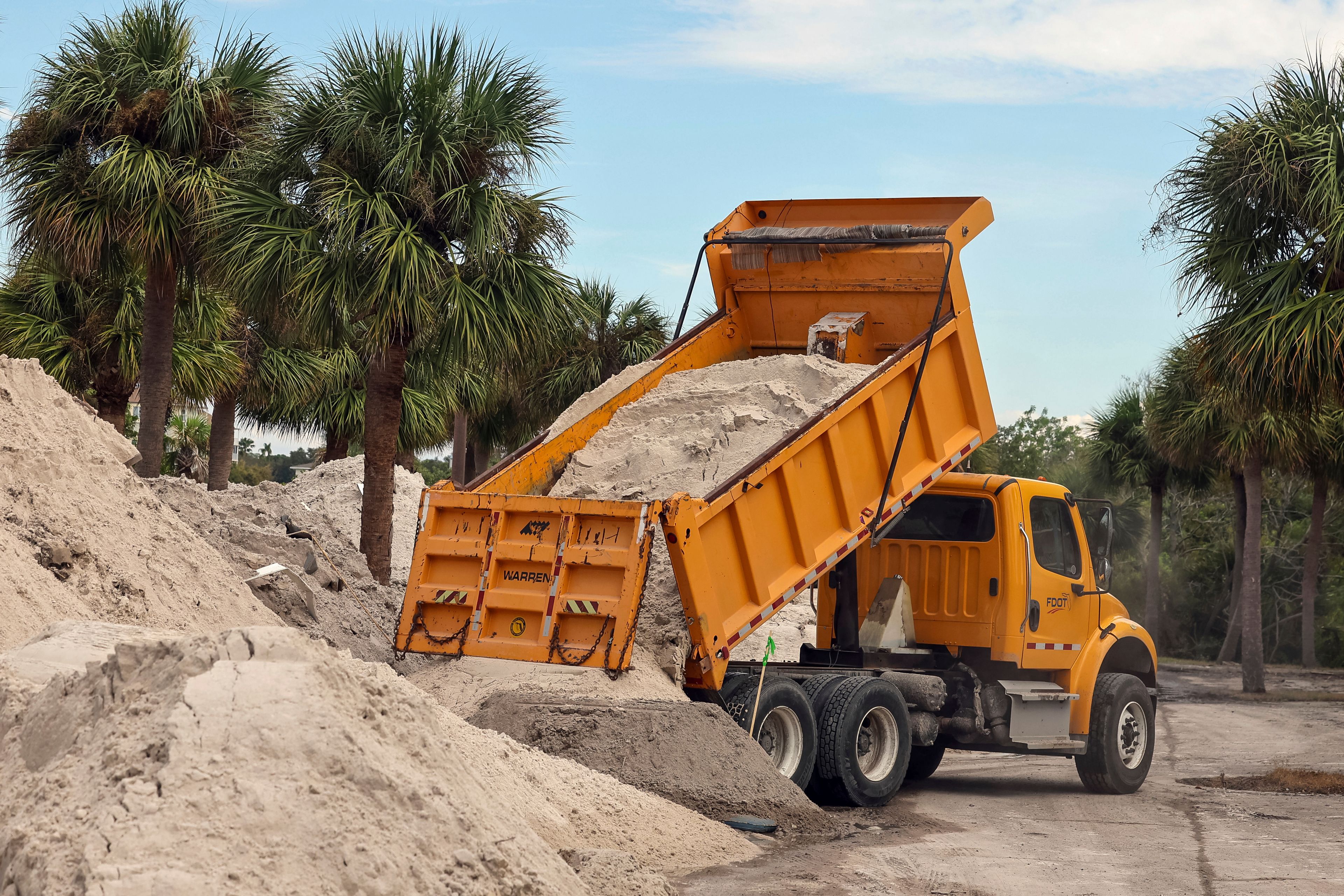 Crews dump sand that was cleared off of the streets from flooding from Hurricane Helene on Wednesday, Oct. 2, 2024, in Indian Shores, Fla. (AP Photo/Mike Carlson)