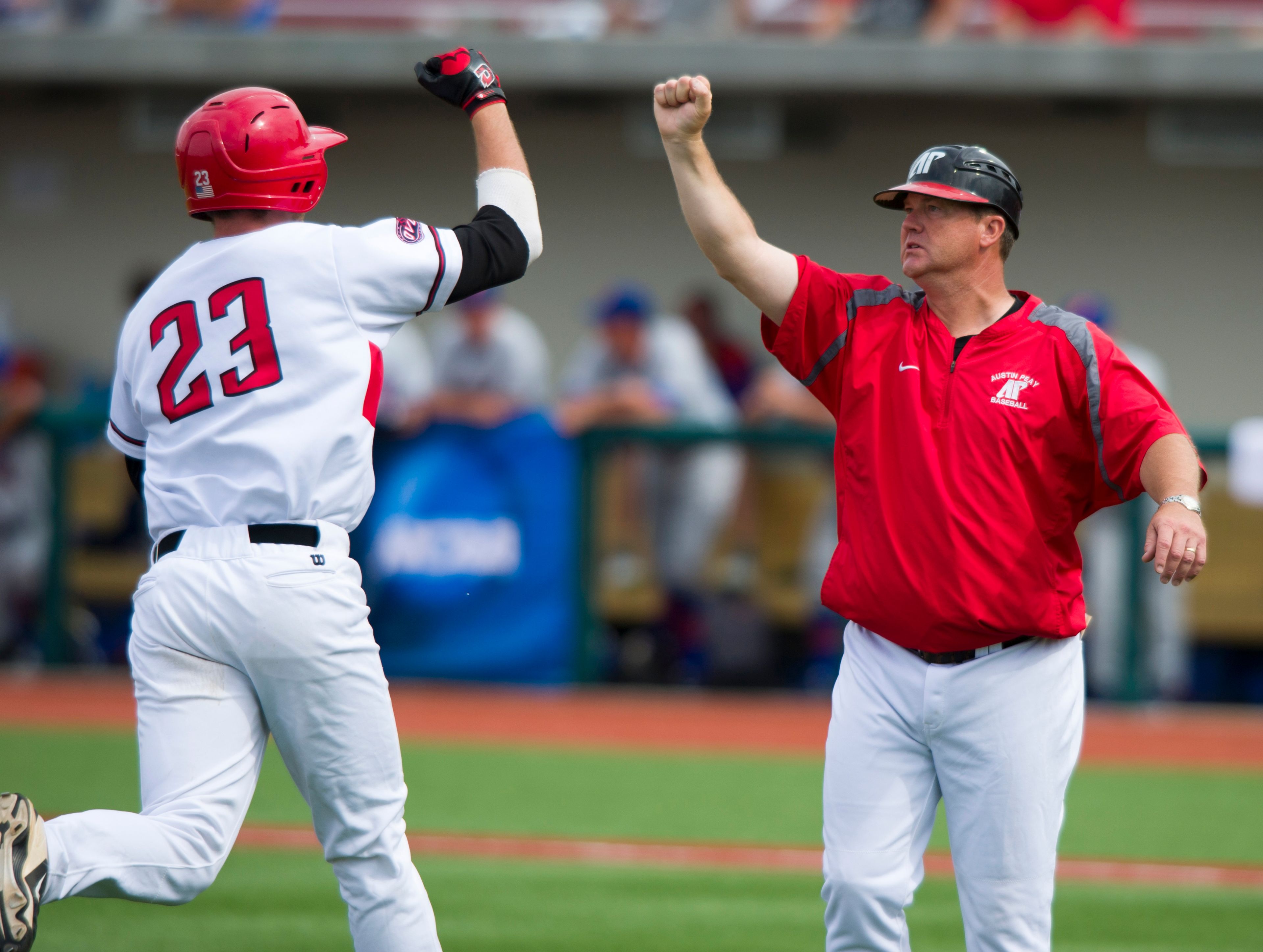 Austin Peay coach Gary McClure fist-bumps Michael Davis on Davis’ three-run, game-winning home run during the eighth inning of an NCAA college baseball tournament regional game May 31, 2013, in Bloomington, Indiana.