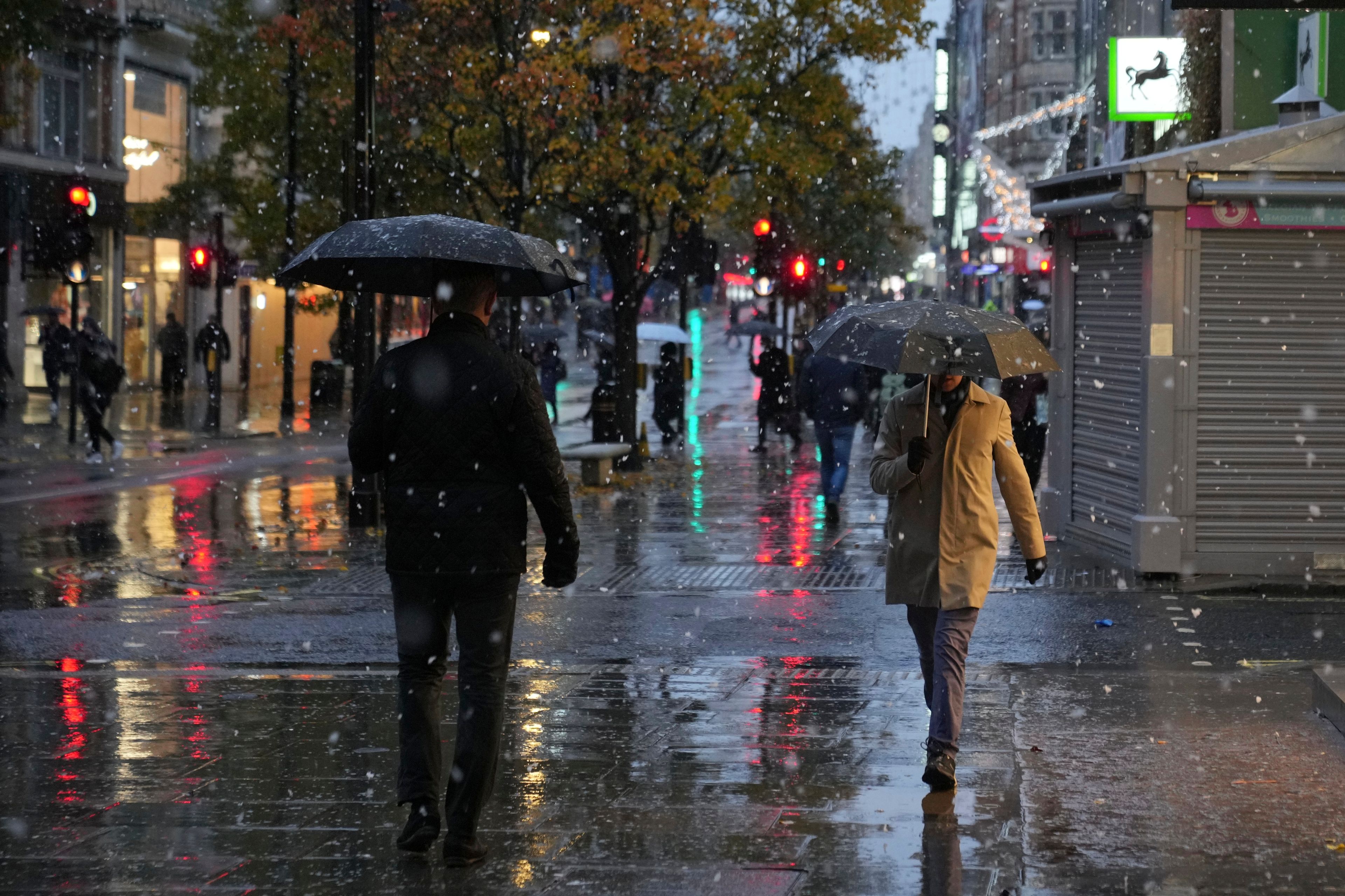 People walk along the Oxford Street as snow falls in London, Tuesday, Nov. 19, 2024. (AP Photo/Kin Cheung)