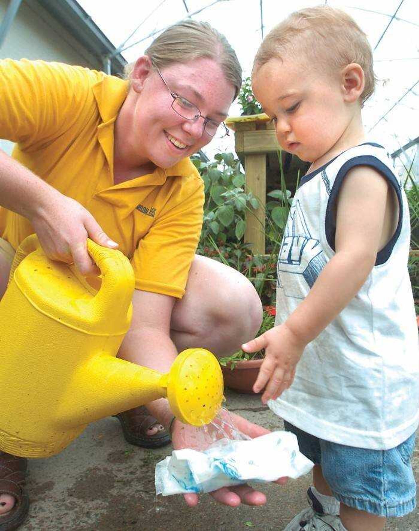 Leah Schnare soaked a paper towel for sprouting lima beans as 16-month-old Kory Siebert watched. (Fred Lynch)