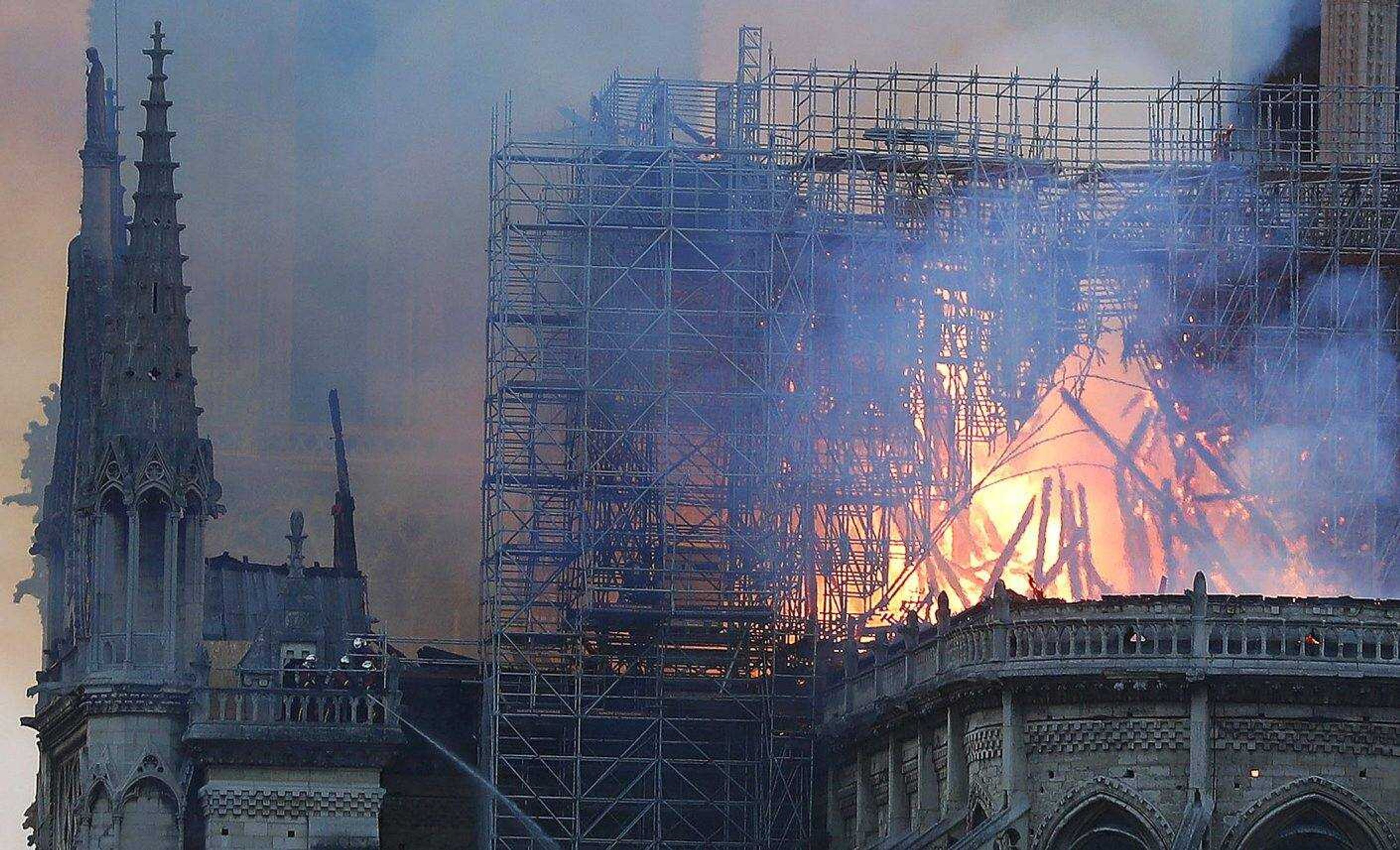 Firefighters tackle the blaze as flames and smoke rise from Notre Dame cathedral as it burns in Paris, Monday, April 15, 2019. Massive plumes of yellow brown smoke is filling the air above Notre Dame Cathedral and ash is falling on tourists and others around the island that marks the center of Paris. (AP Photo/Thibault Camus)