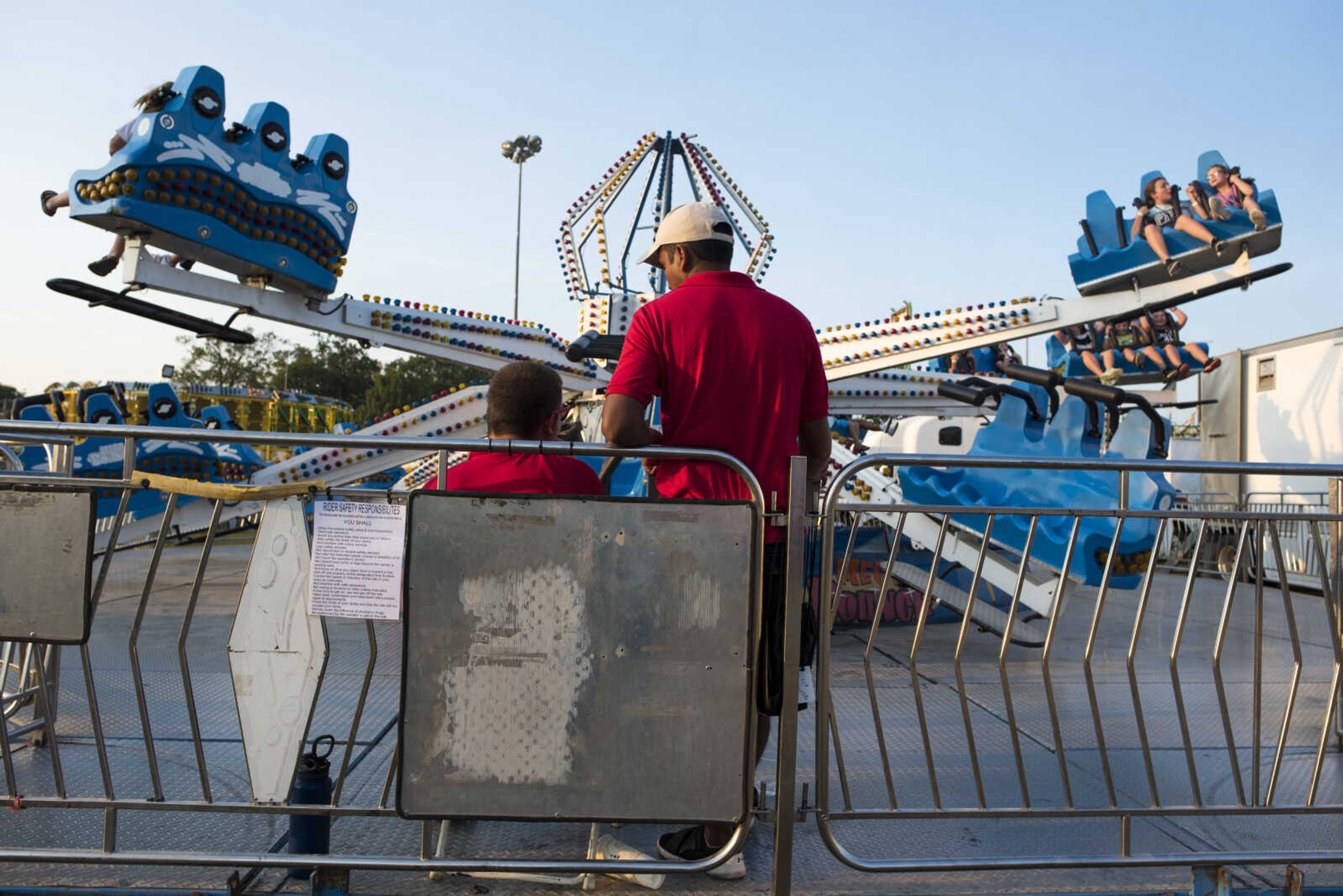 Midway ride operators stand together at the operator's panel as the "Mega Bounce" ride spins Sept. 9, 2019, at the SEMO District Fair in Cape Girardeau.