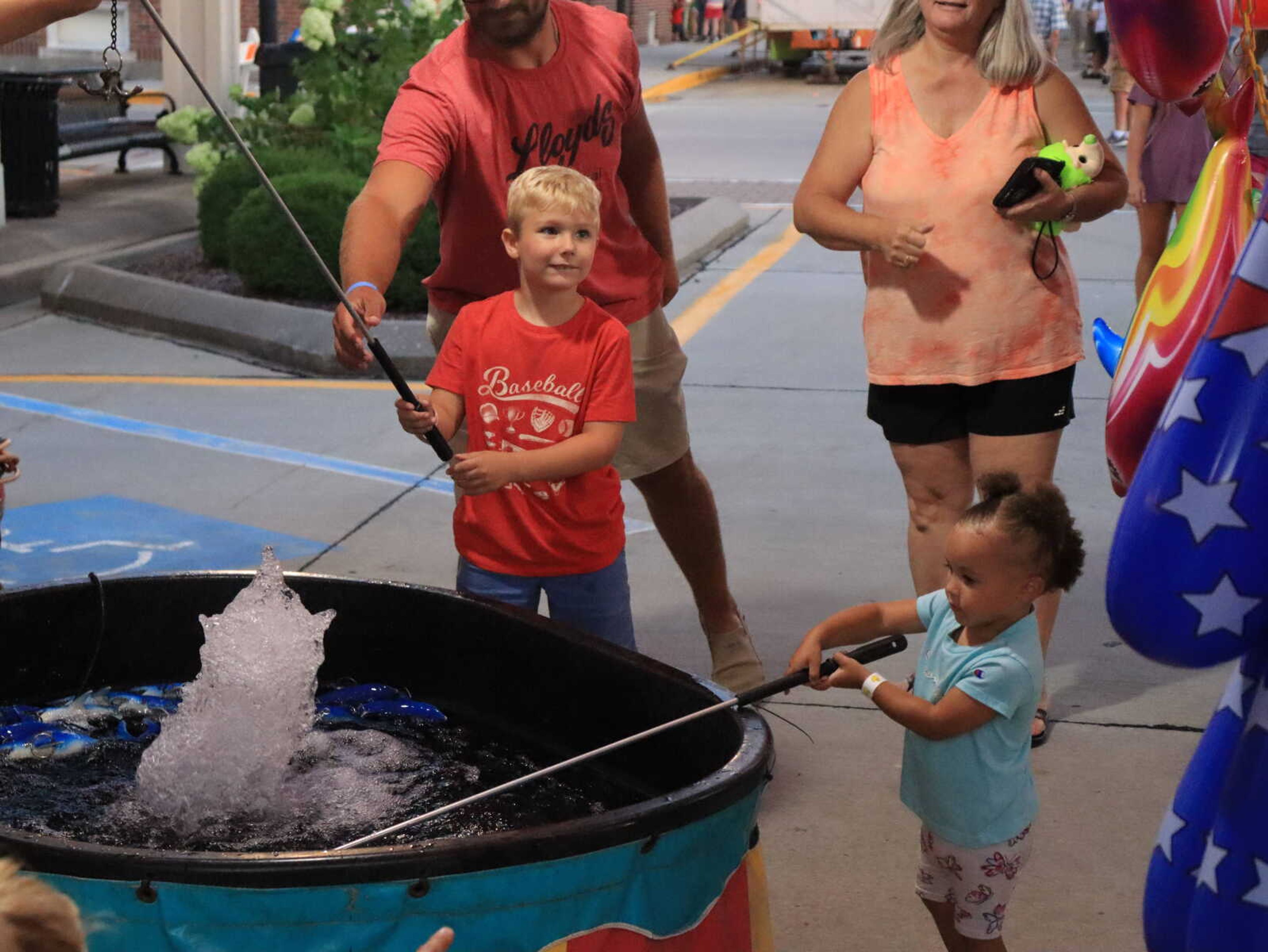 Children playing a fishing game while parents stand to watch for their next catch at Jackson Homecomers.