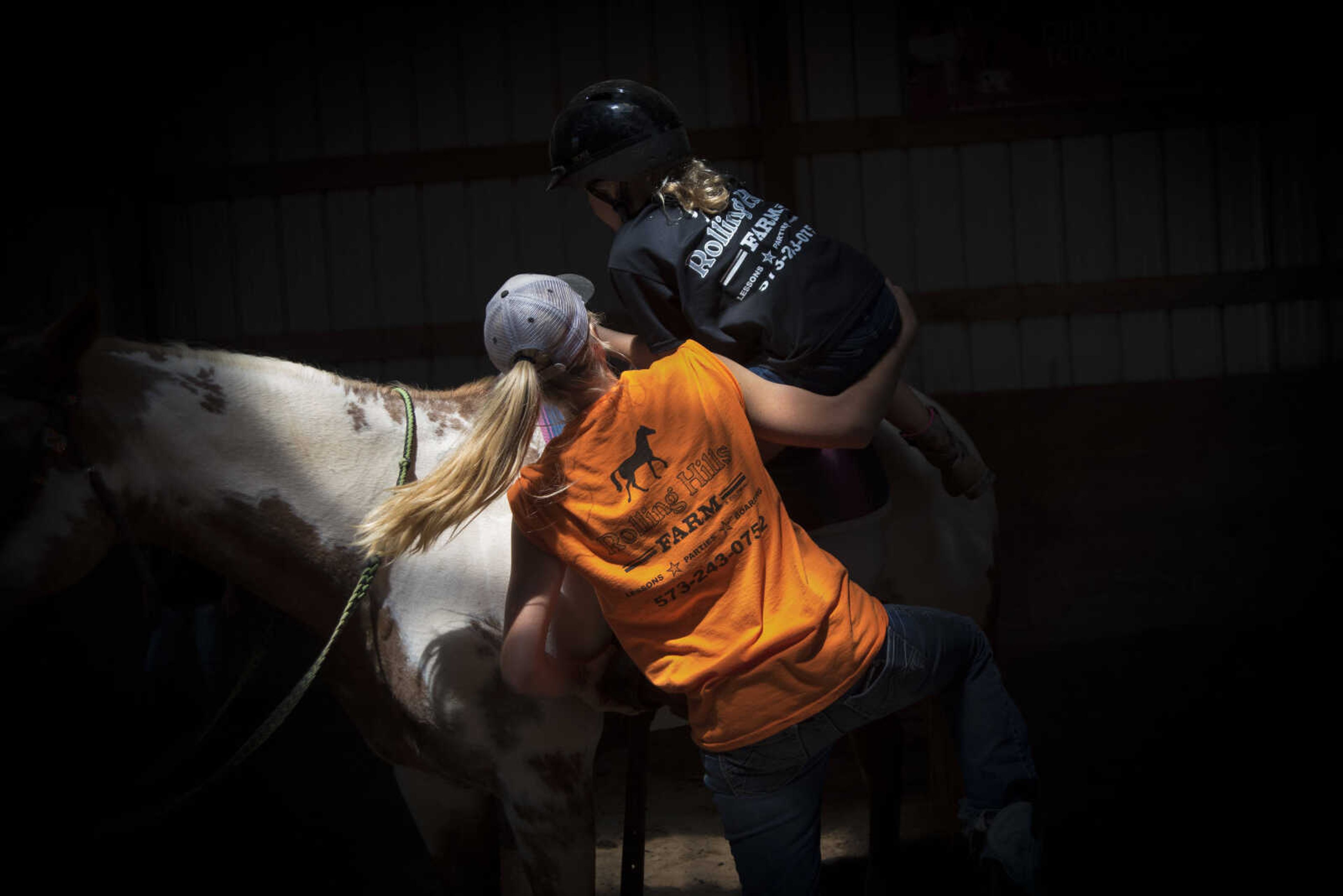 Kristin Carlton, left, helps out Lilli Boitnott, 9, up on her horse during the Rolling Hills Youth Day Camp Wednesday, June 7, 2017 in Cape Girardeau.