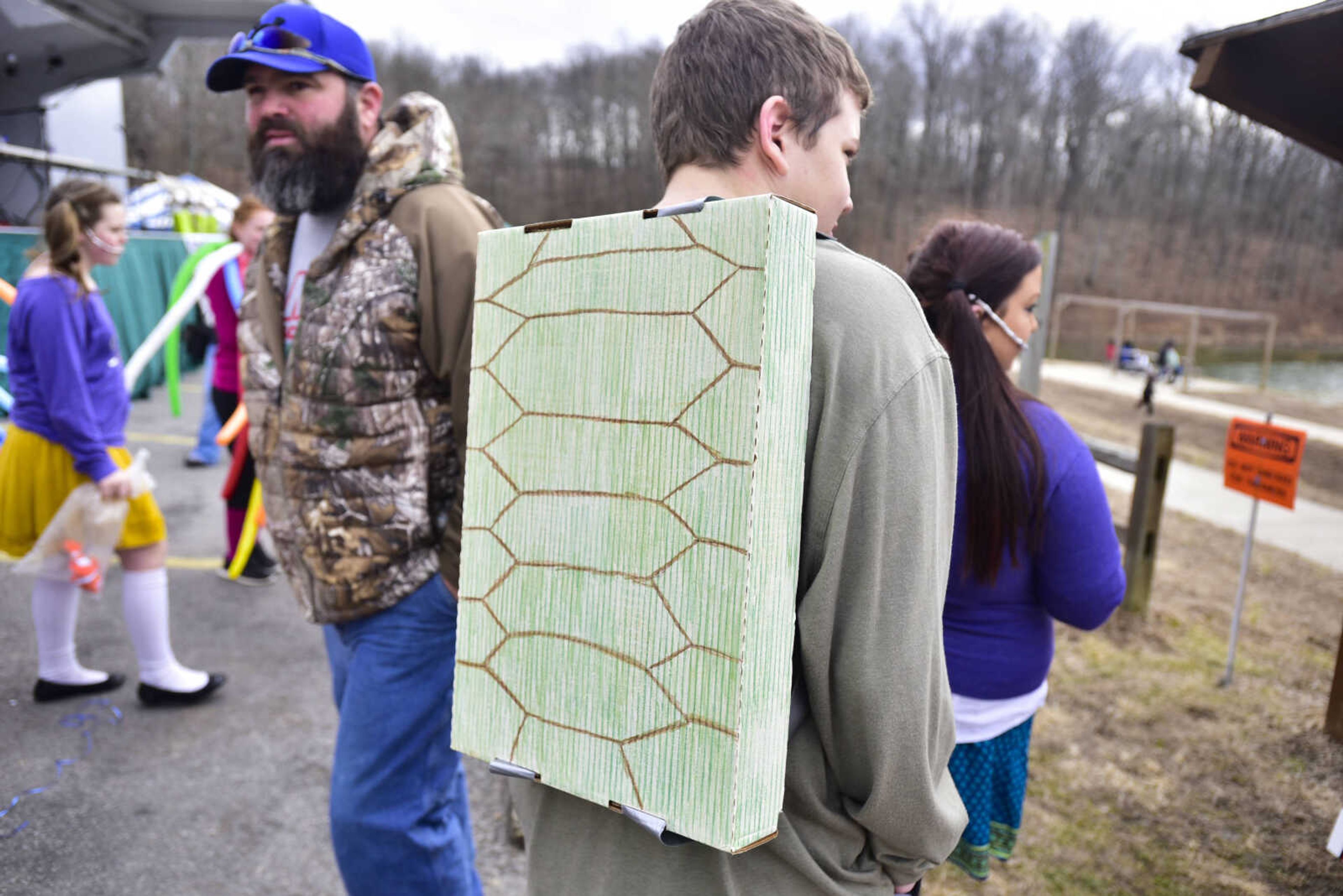 A cardboard turtle shell hangs from the back of Ryan Birman, 16, of Delta High School, as he looks towards Lake Boutin while dressed as "Crush" during the Polar Plunge benefit for Special Olympics Missouri on Saturday, Feb. 3, 2018, at Trail of Tears State Park.