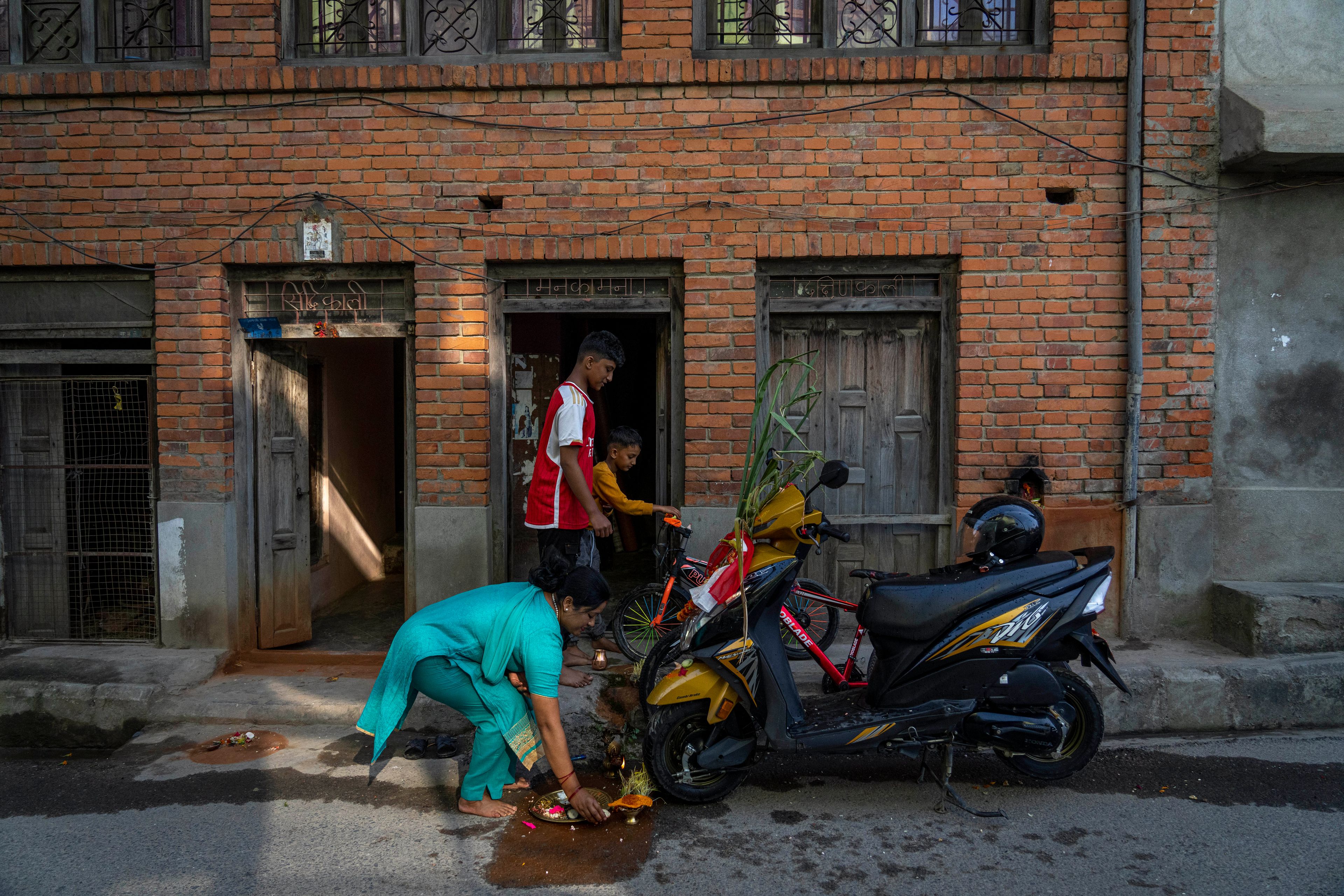 A family performs rituals to their vehicles during Dashain festival in Bhaktapur, Nepal, Friday, Oct. 11, 2024. The festival commemorates the slaying of a demon king by Hindu goddess Durga, marking the victory of good over evil. (AP Photo/Niranjan Shrestha)