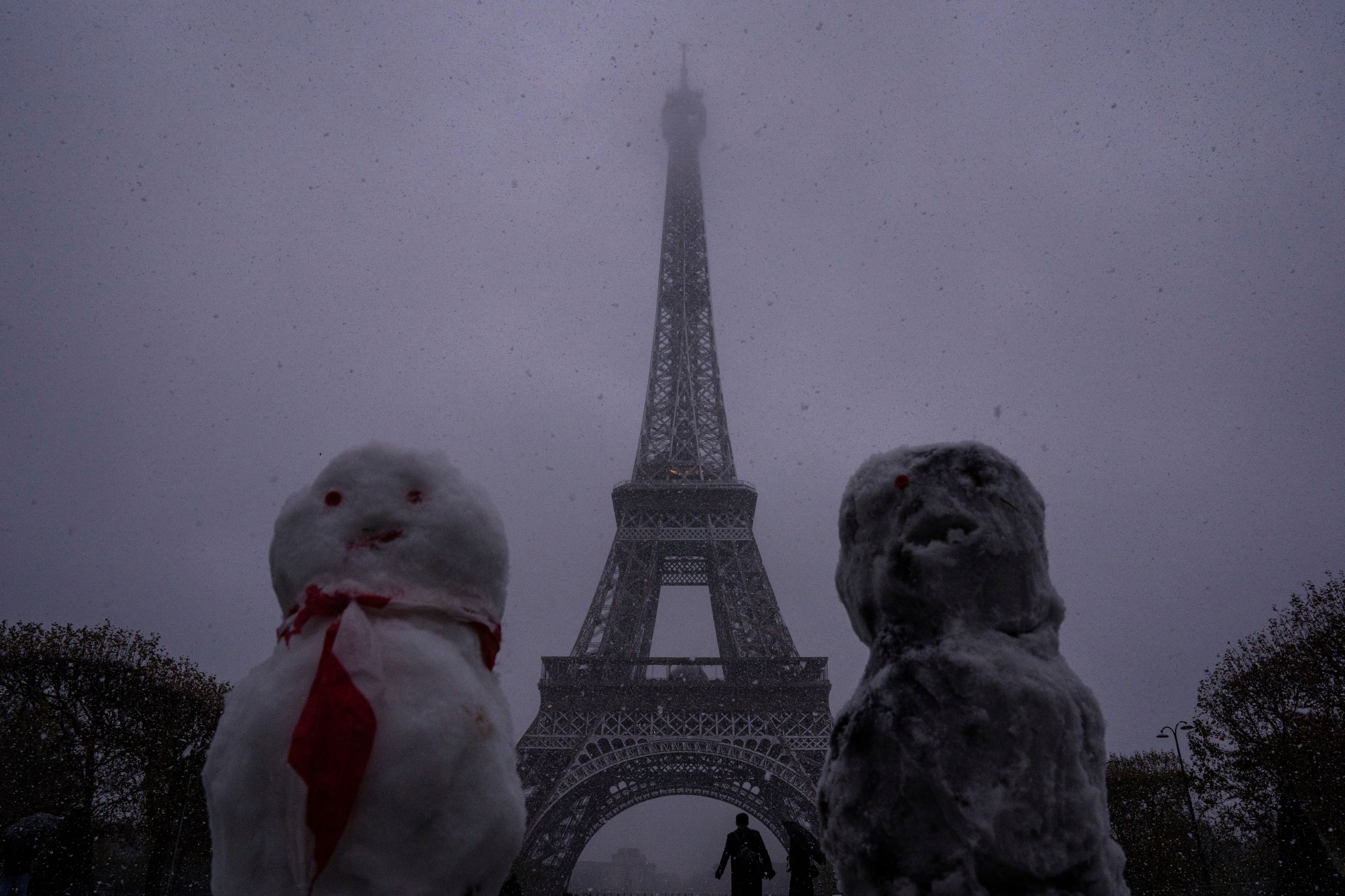 Snow figures are seen near to the Eiffel Tower as snow falls in Paris, Thursday, Nov. 21, 2024. (AP Photo/Louise Delmotte)