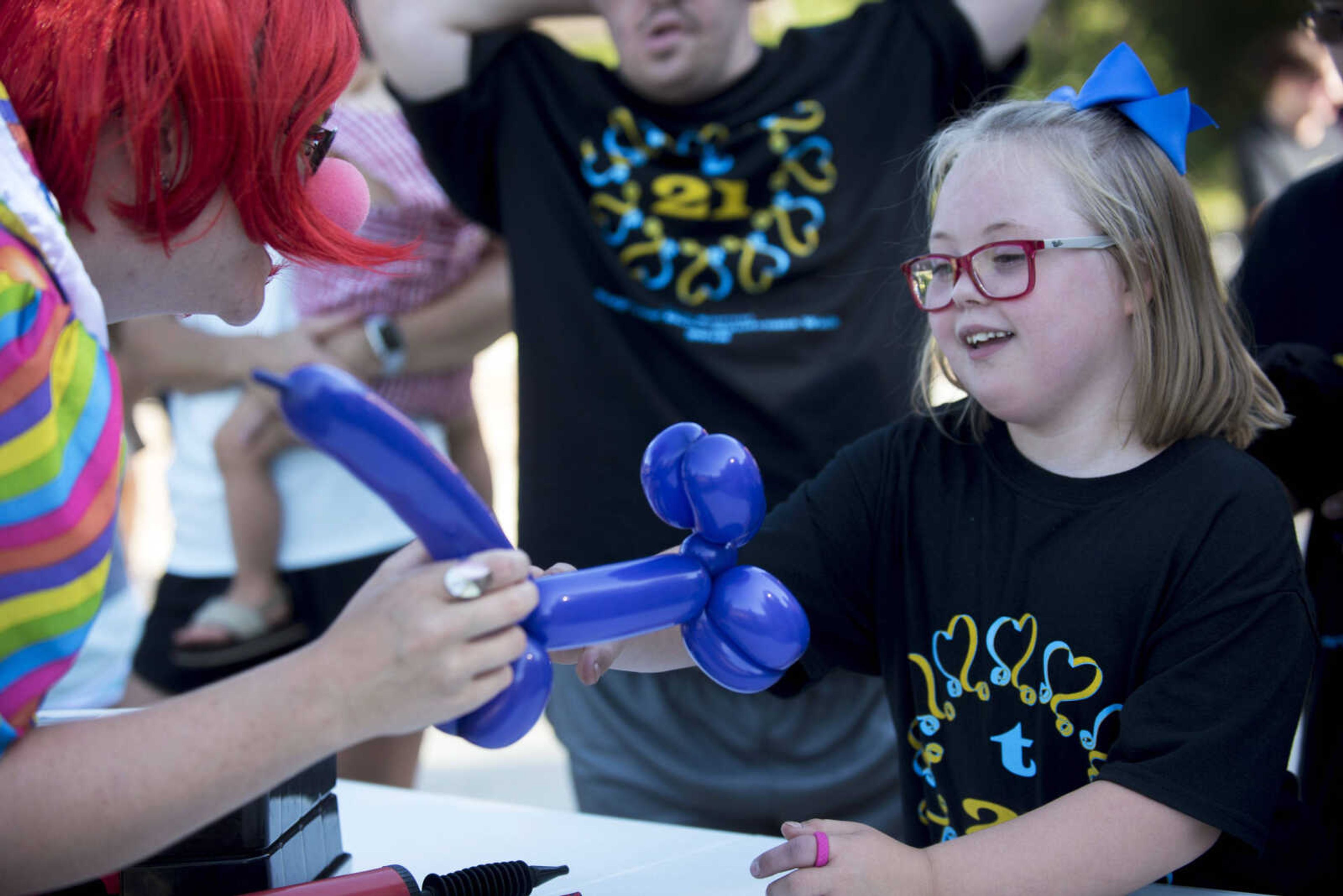 Lilly Stephens, 9, right, gets a balloon puppy from clown Kelli Conner during the Heartland Down Syndrome Association's 10th annual Step Up for Down Syndrome walk in Capaha Park Saturday.