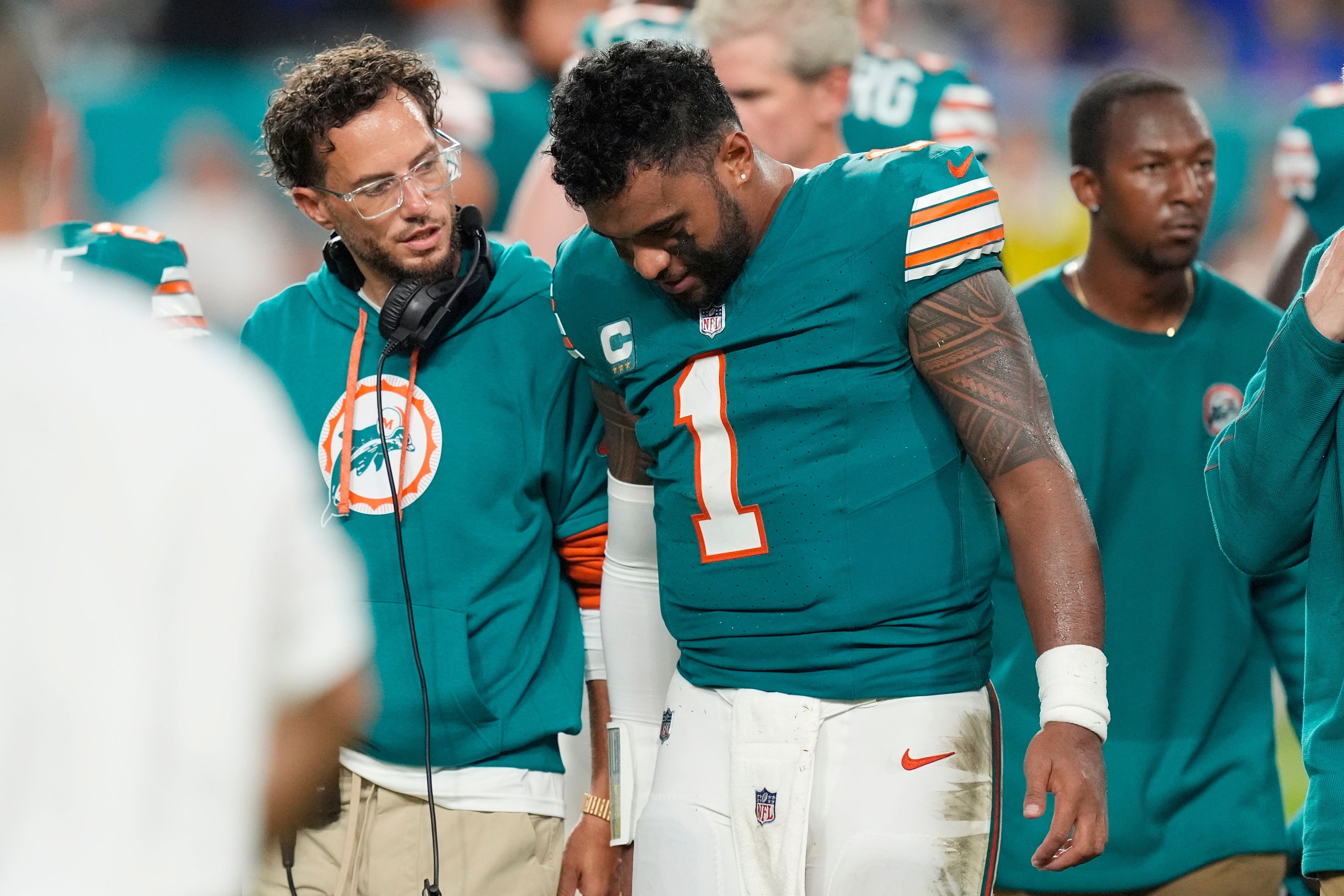 Miami Dolphins head coach Mike McDaniel talks to quarterback Tua Tagovailoa (1) as he leaves the game after suffering a concussion during the second half of an NFL football game against the Buffalo Bills, Thursday, Sept. 12, 2024, in Miami Gardens, Fla. (AP Photo/Rebecca Blackwell)