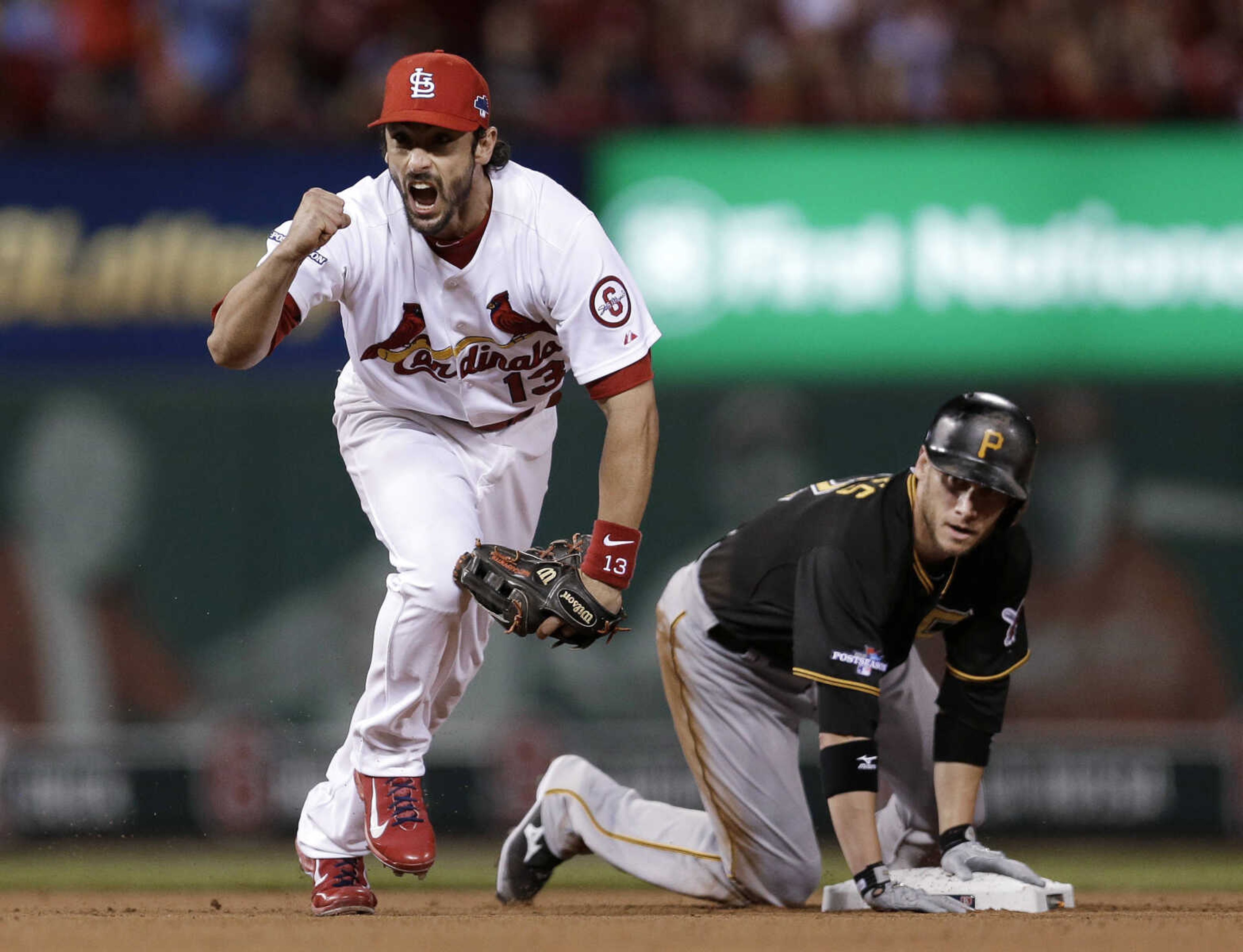 St. Louis Cardinals second baseman Matt Carpenter, left, celebrates after turning a double play as Pittsburgh Pirates' Clint Barmes, right, watches the play at first base that ended the top of the sixth inning in Game 5 of a National League baseball division series, Wednesday, Oct. 9, 2013, in St. Louis. Starling Marte hit into the double play. (AP Photo/Jeff Roberson)