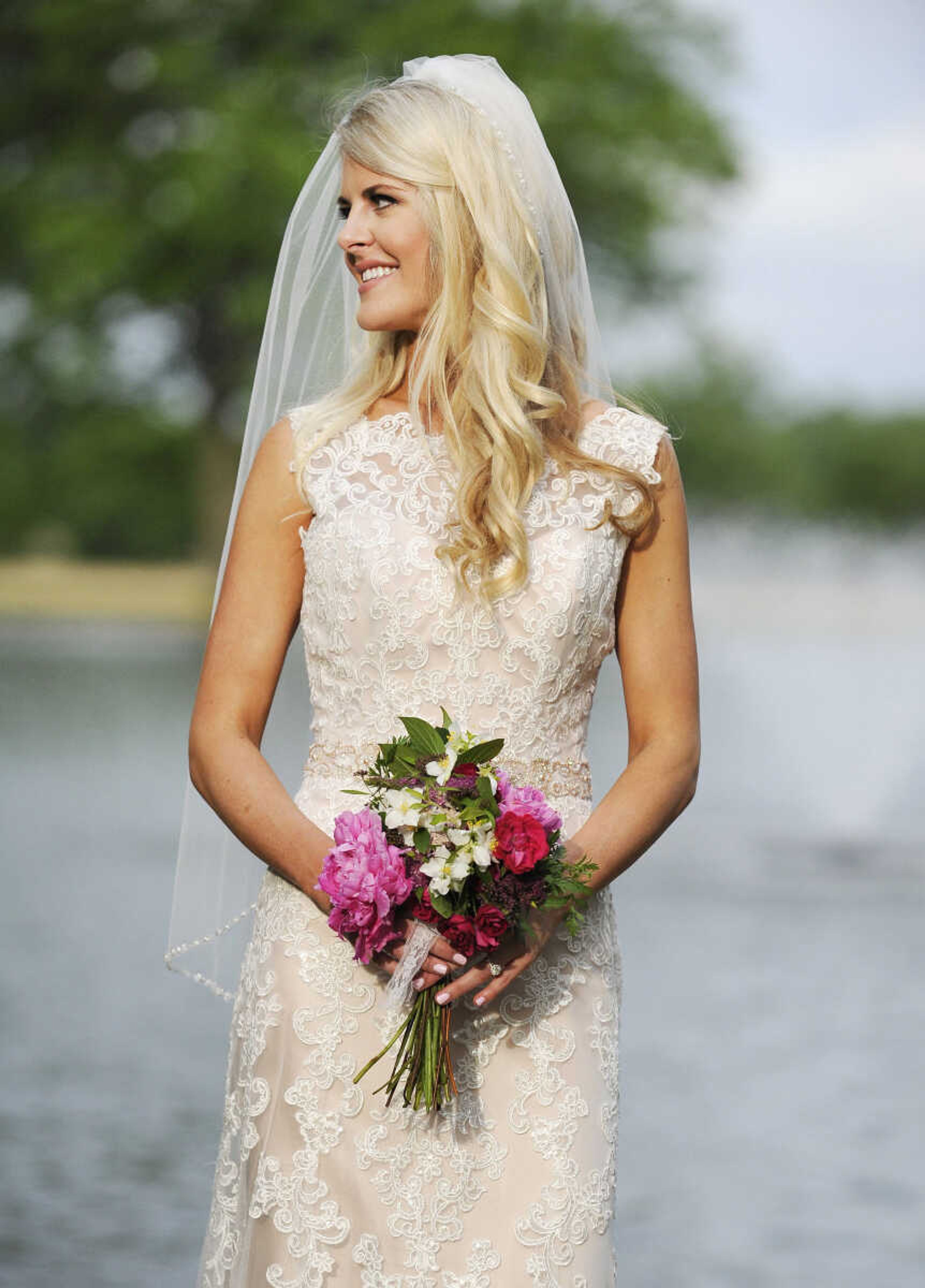 On Paige: This ivory/blush David Tutera "Rumer" gown comes in two pieces, with a Schiffli lace cage dress over a satin A-line dress. The gown also features a tulle skirt, and illusion and scalloped lace bateau neckline and a beaded sweetheart bodice and waisteband. The back has a deep V with crystal button closures and a chapel-length train. The dress is accessorized with a Bel Aire Bridals fingertip-length veil edged with pearls, bugle beads and rhinestones. All available at The Andrew Jackson in Cape Girardeau.