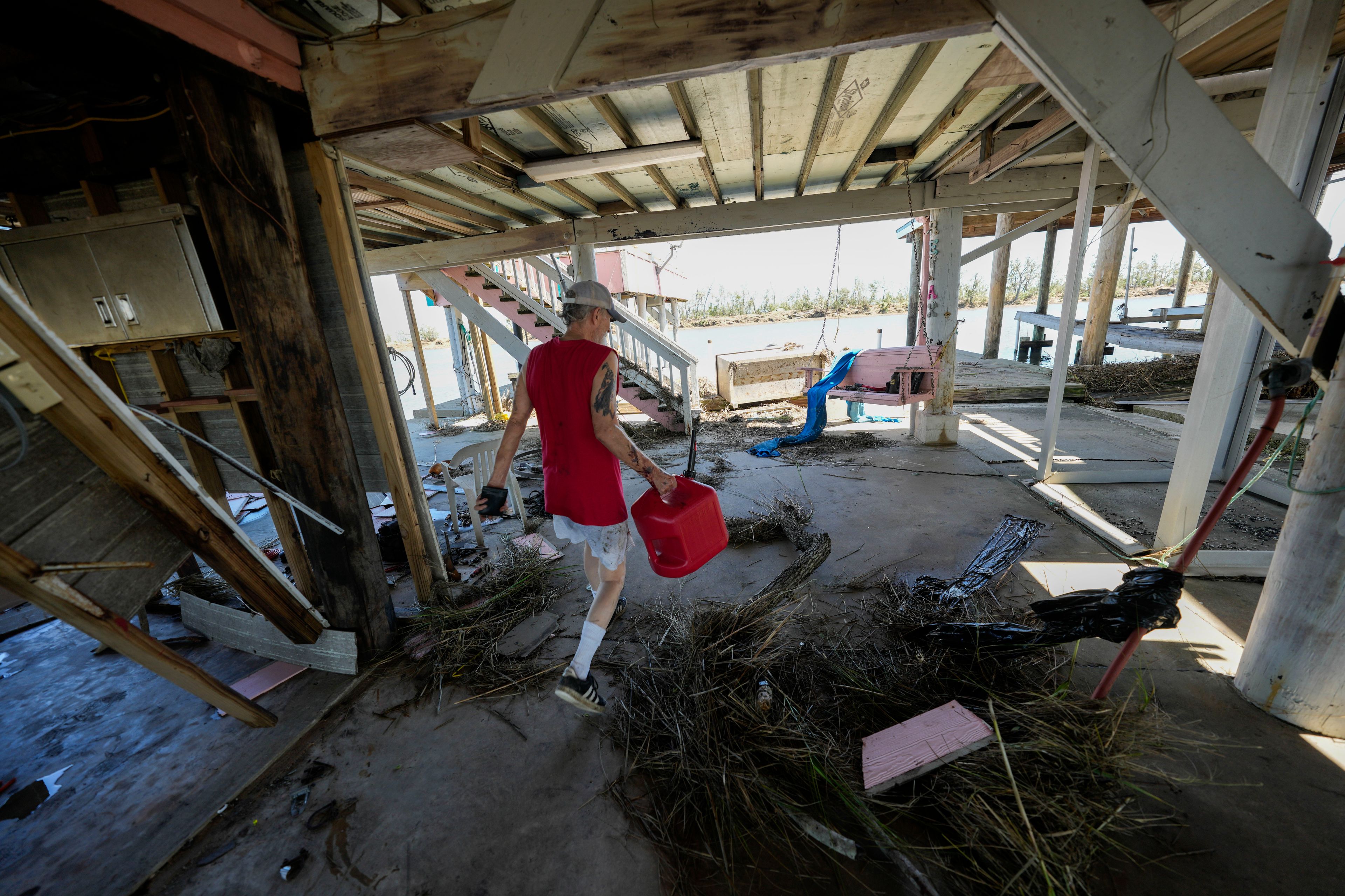 Resident Bill Andrews walks through debris under his home in the aftermath of Hurricane Francine in Cocodrie, La., Thursday, Sept. 12, 2024. (AP Photo/Gerald Herbert)