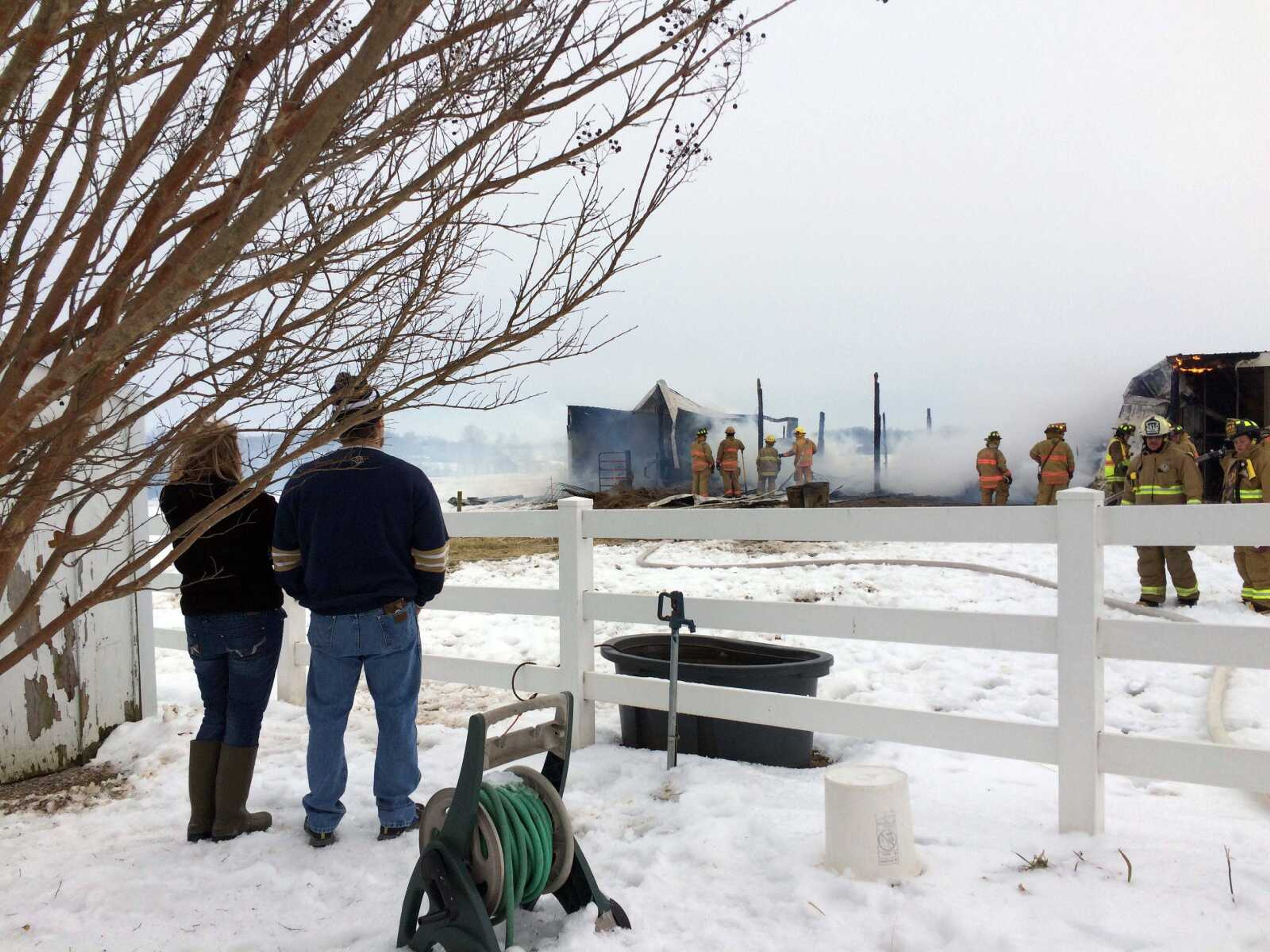 Emily and Doug Scheper watch as firefighers try to extinguish lingering flames in their barn after it was destroyed by fire Sunday afternoon. (Savanna Maue)