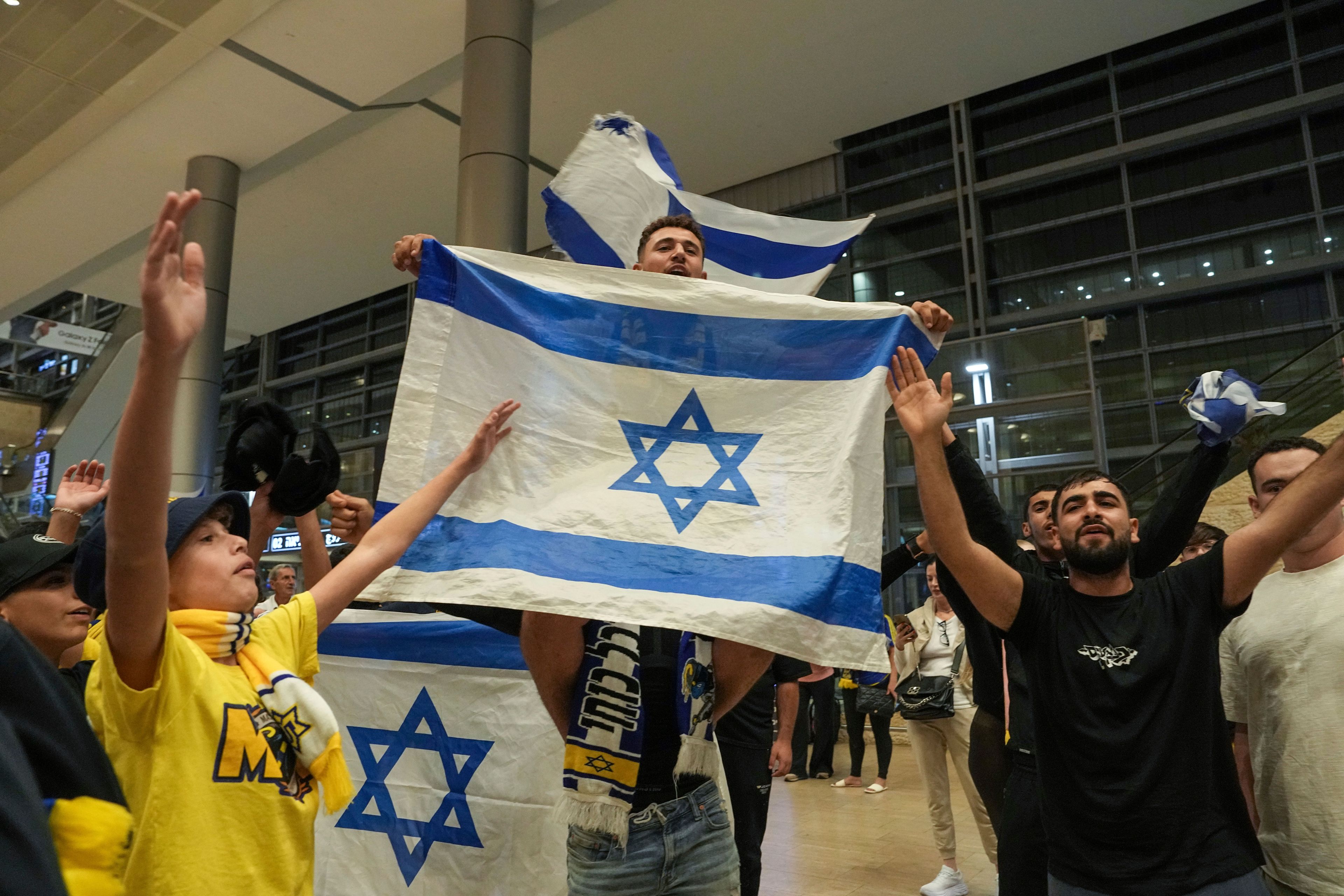 People welcome Maccabi Tel Aviv soccer fans as they arrive at Israel's Ben-Gurion International Airport on a flight from Amsterdam, where Israeli soccer fans were attacked following a match between the Israeli club and Ajax Amsterdam, in Lod, Israel, Friday, Nov. 8, 2024. (AP Photo/Tsafrir Abayov)