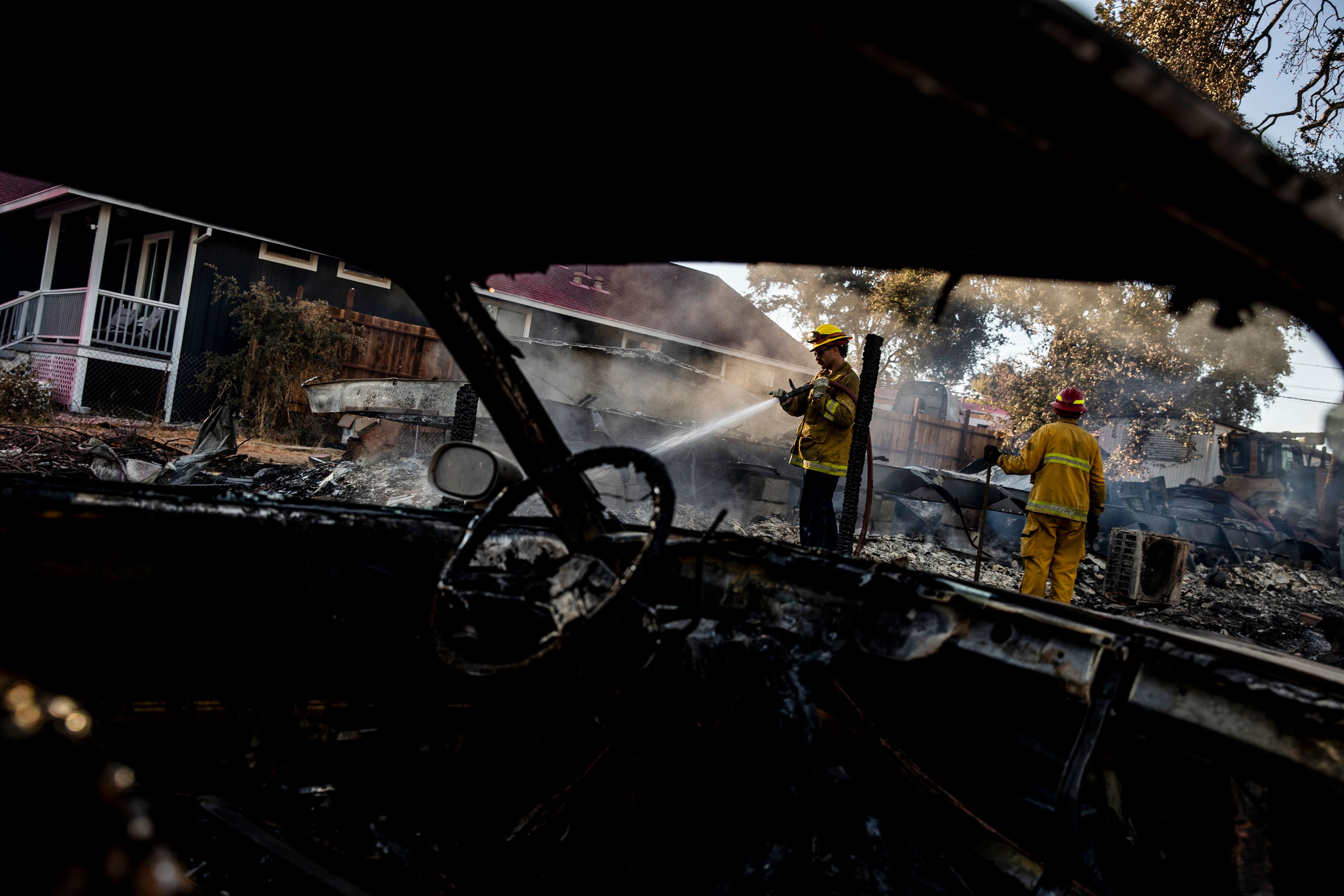 A Cal Fire firefighter puts water on a smoldering structure during the Boyles fire in Clearlake, Calif., Sunday, Sept. 8, 2024. (Stephen Lam/San Francisco Chronicle via AP)