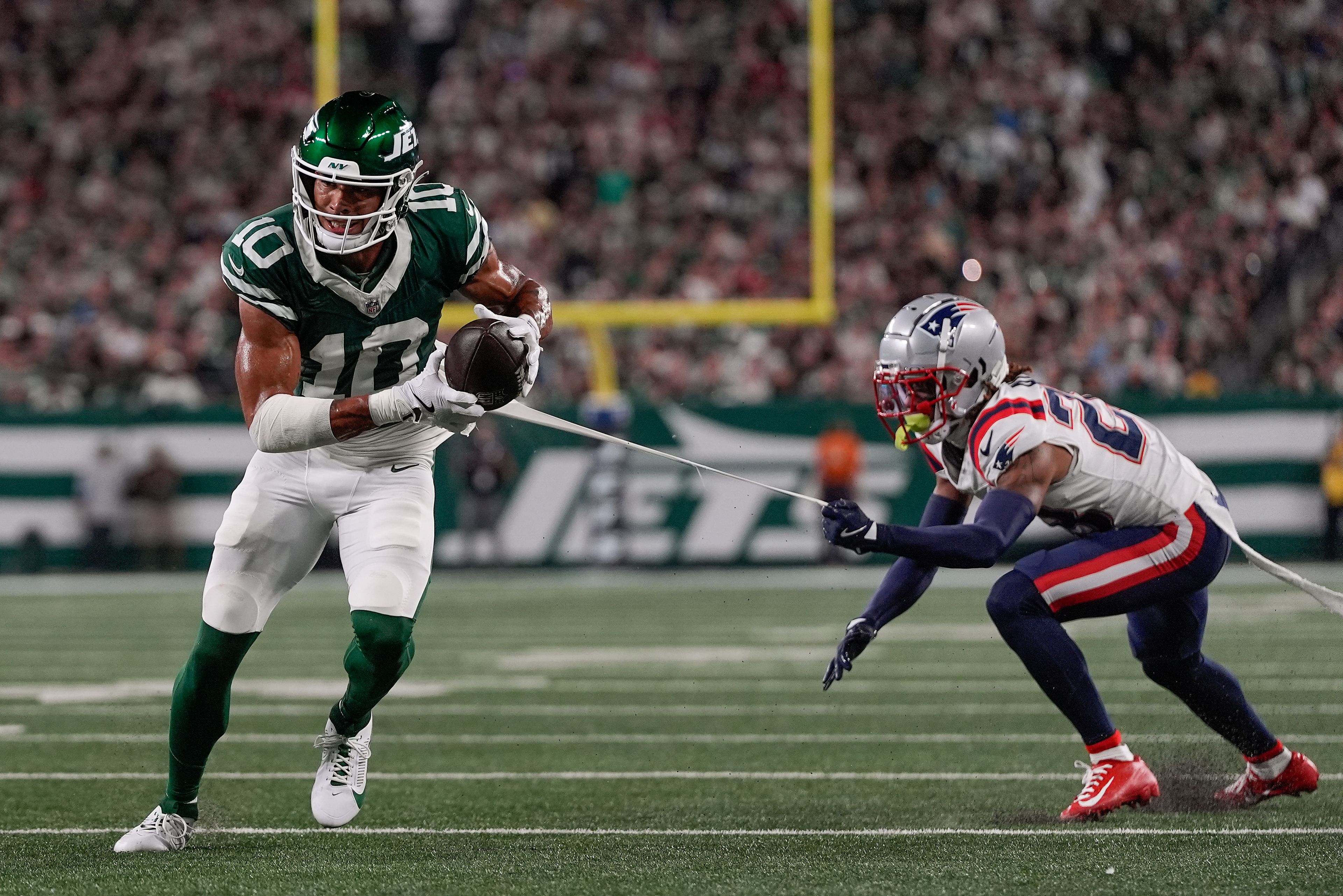 New York Jets wide receiver Allen Lazard (10) runs for a touchdown despite the efforts of New England Patriots cornerback Alex Austin (28) during the first quarter of an NFL football game, Thursday, Sept. 19, 2024, in East Rutherford, N.J. (AP Photo/Julia Demaree Nikhinson)