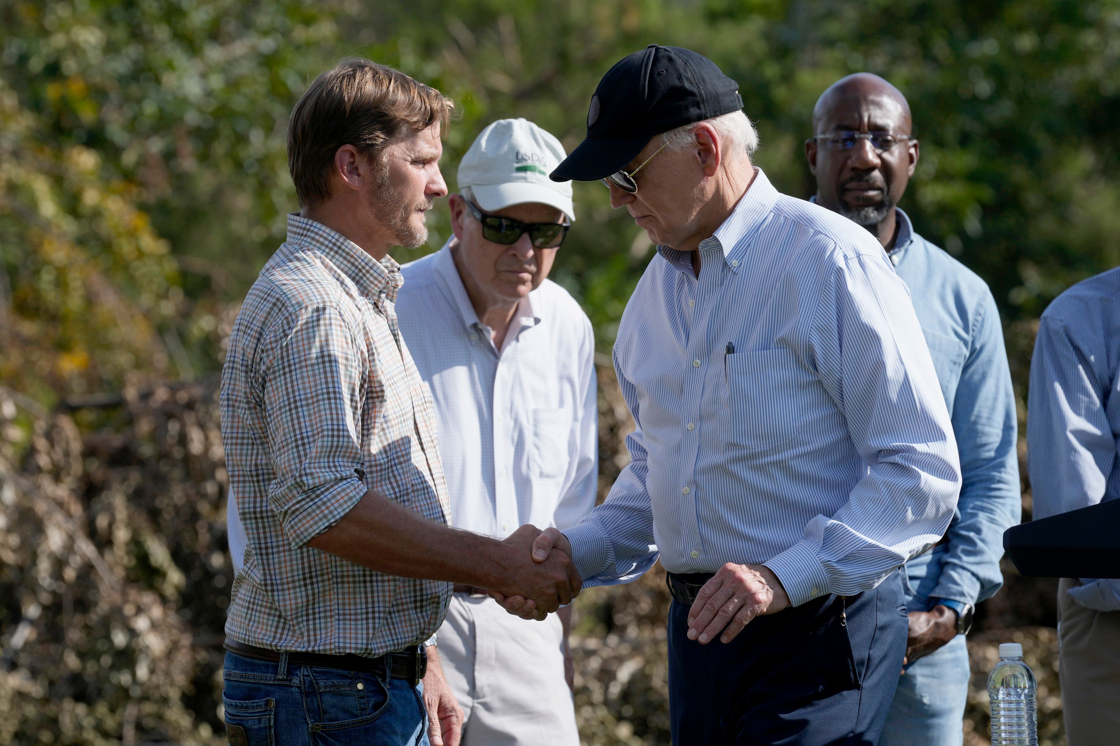 FILE - President Joe Biden, right, shakes hands with Buck Paulk, property manager of Shiloh Pecan Farm, after he spoke at the farm in Ray City, Ga., Oct. 3, 2024, as part of his trip to see areas impacted by Hurricane Helene. Looking on at right is Sen. Raphael Warnock, D-Ga. (AP Photo/Susan Walsh, File)