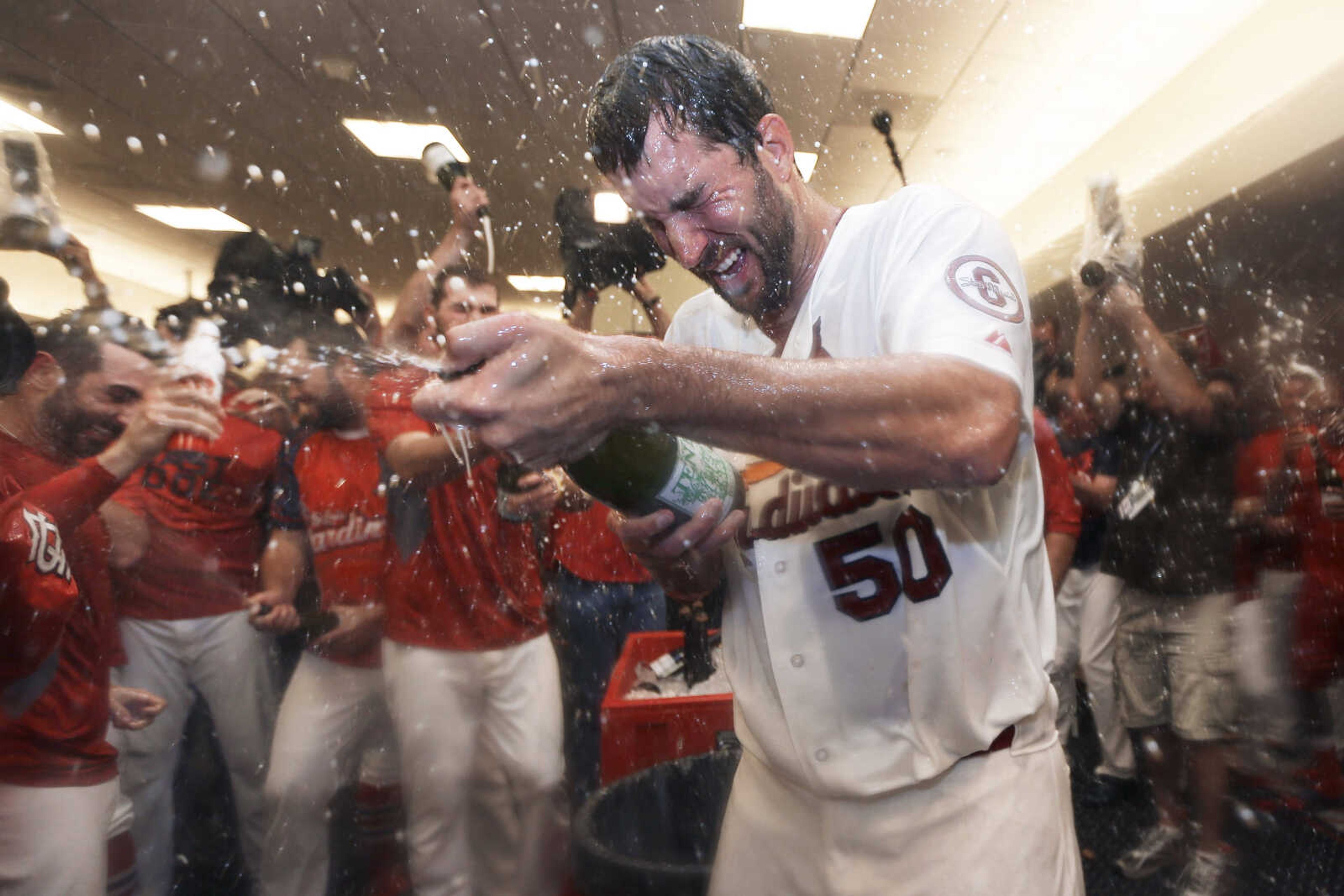 St. Louis Cardinals pitcher Adam Wainwright (50) and teammates celebrate in the locker room after the Cardinals defeated the Pittsburgh Pirates to win Game 5 in a National League baseball division series, Wednesday, Oct. 9, 2013, in St. Louis. The Cardinals won 6-1, and advanced to the NL championship series against the Los Angeles Dodgers. (AP Photo/Jeff Roberson)