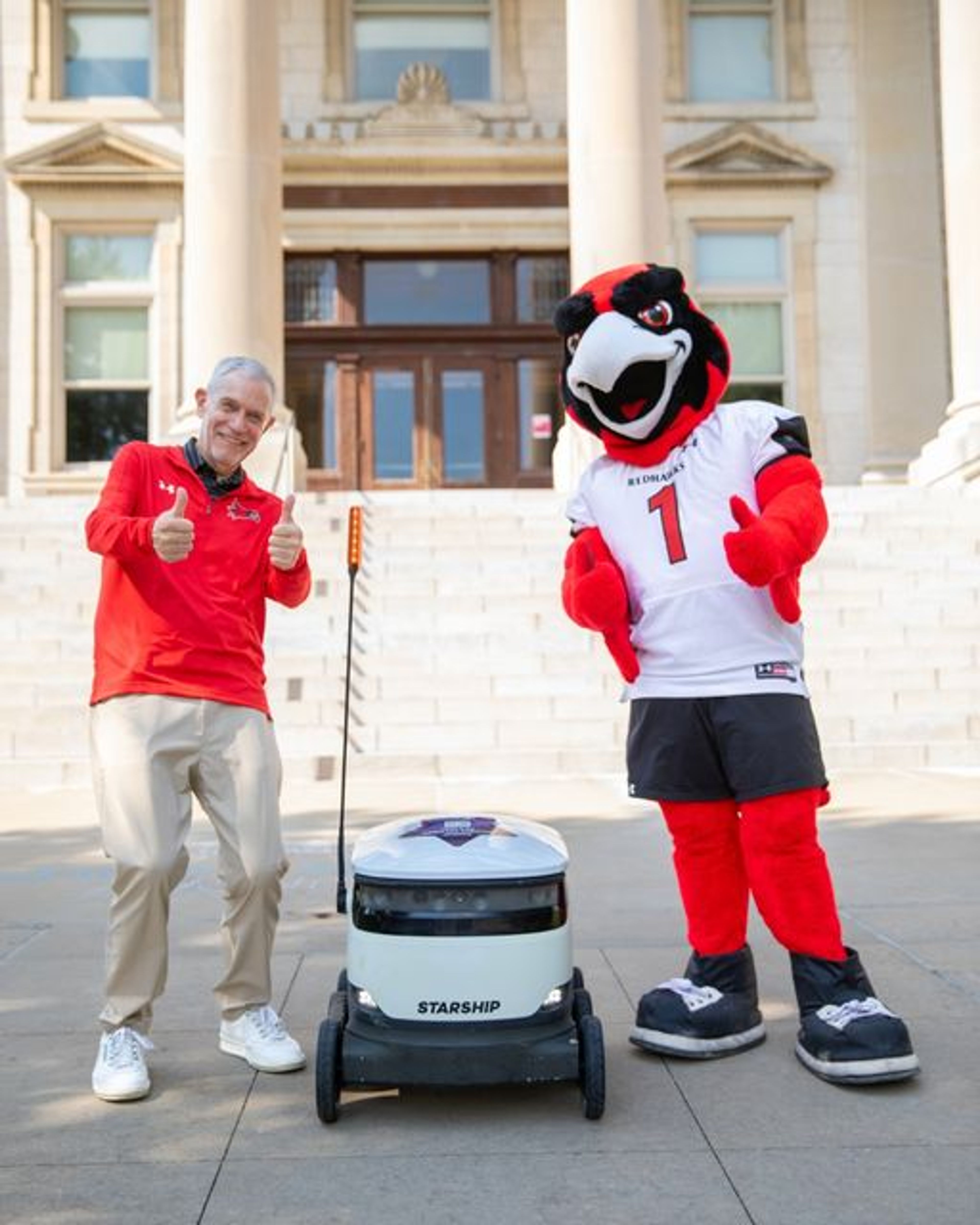 Southeast Missouri State University president Carlos Vargas and Rowdy the Redhawk show off one of the university’s new Starship food delivery robots. 