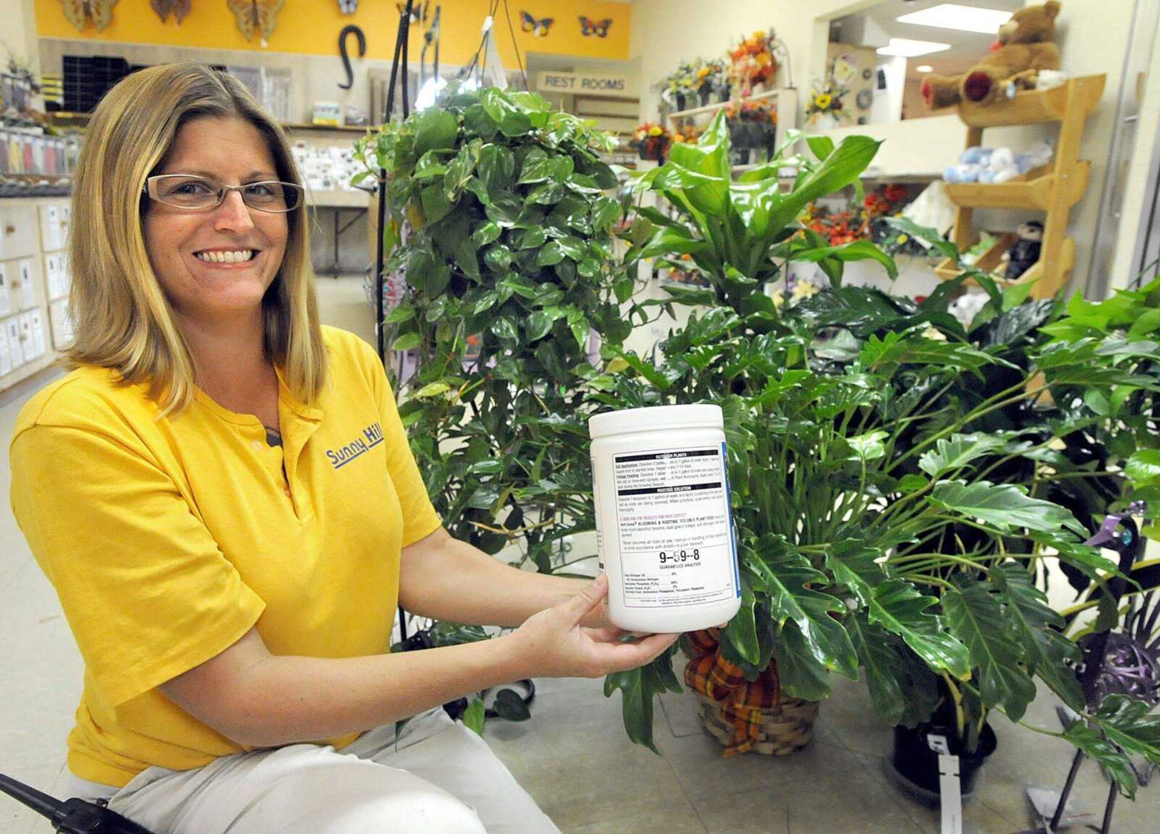 Sunny Hill's Melissa LaPlant holds a container of Blooming &amp; Rooting soluble plant food 9-59-8 that can be used for house plants. (Laura Simon)