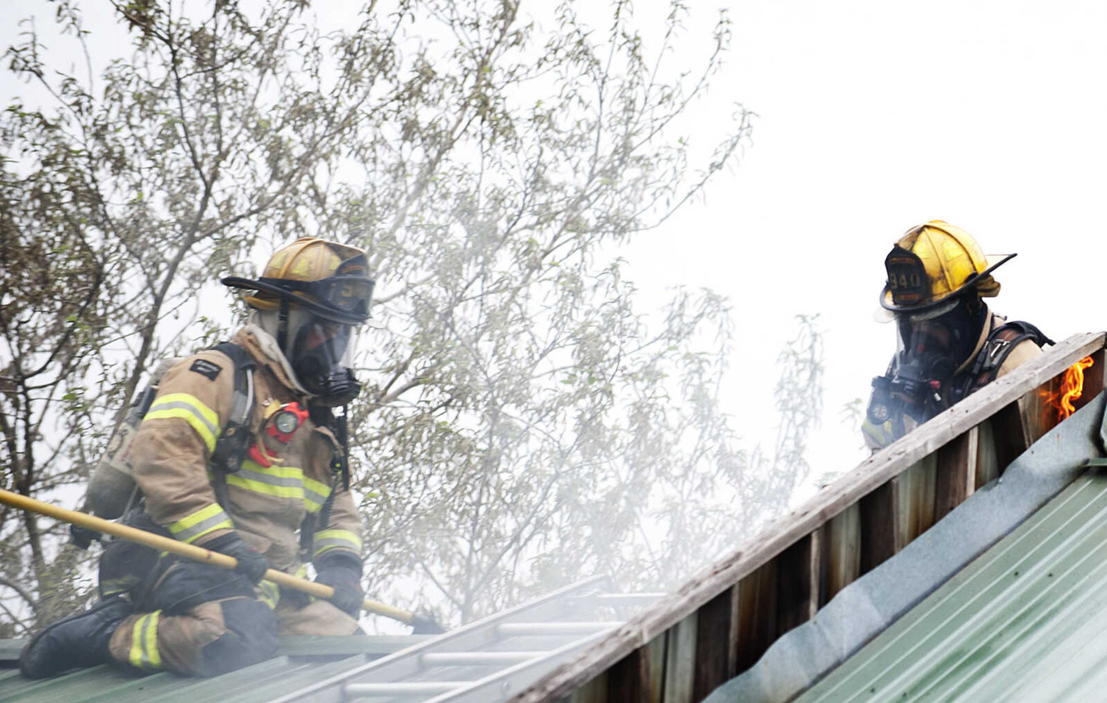 Cape Girardeau firefighters use a saw to cut through the roof as they battle a structure fire at 710 Morgan Oak  St., Tuesday, April 29, in Cape Girardeau. A Cape Girardeau Police officer saw the fire and called it in at 1:16 p.m. The building contained two apartments that were home to five people, though no one was home at the time of the fire. The cause of the fire is under investigation.