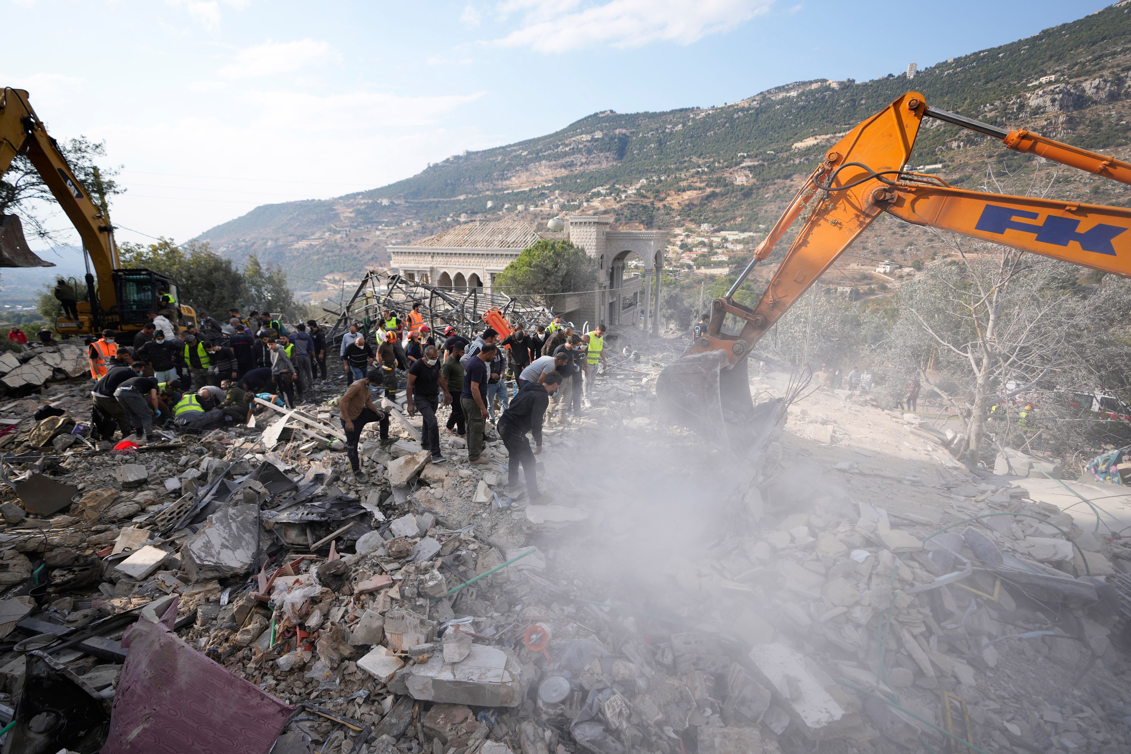 Rescue workers use excavators to remove the rubble of a destroyed house hit in an Israeli airstrike, as they search for victims in Aalmat village, northern Lebanon, Sunday, Nov. 10, 2024. (AP Photo/Hassan Ammar)