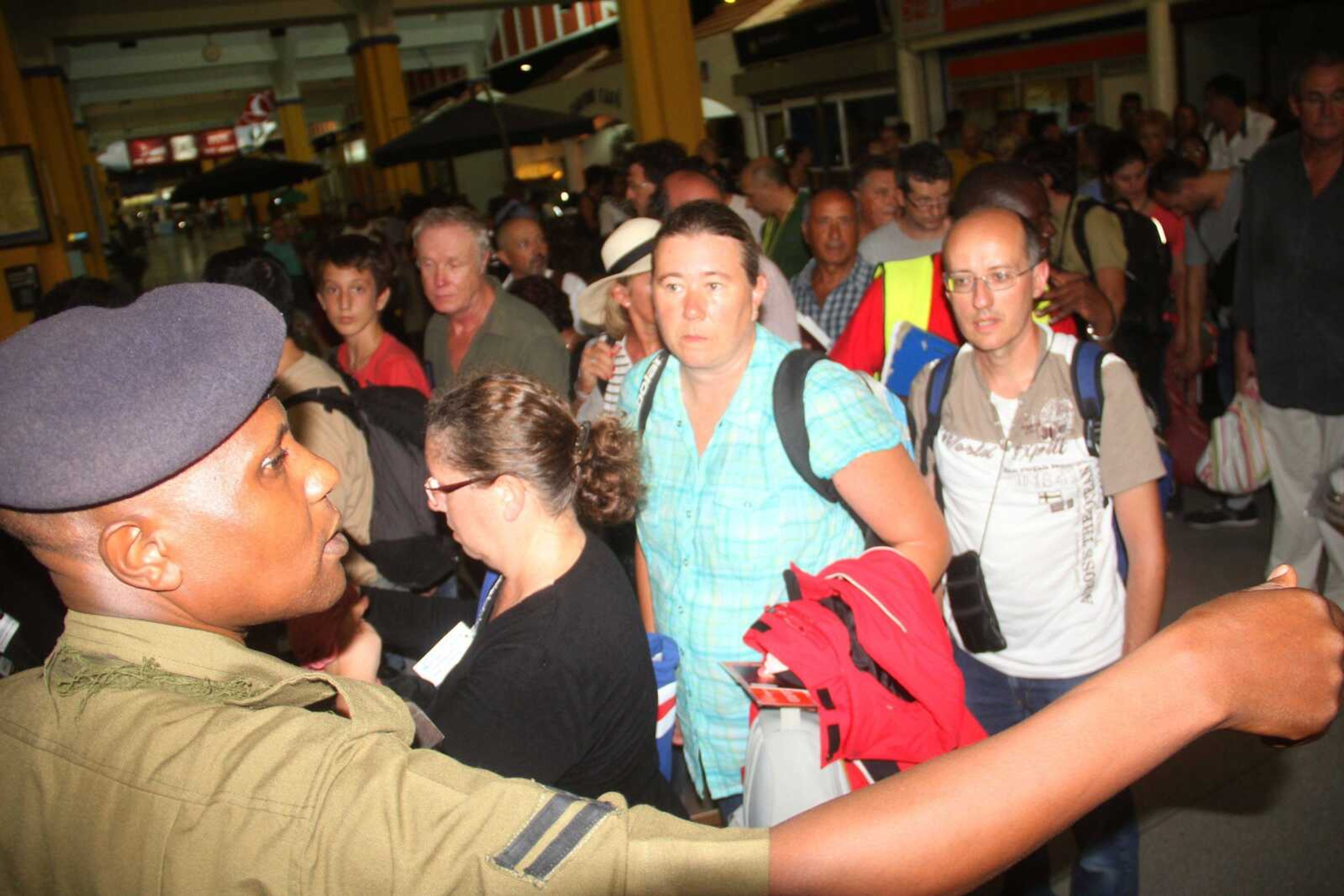 A Kenyan Police officer keeps vigil Sunday as passengers go through security screening at Moi International Airport Mombasa Kenya after their earlier flight was involved in a bomb scare. (Associated Press)