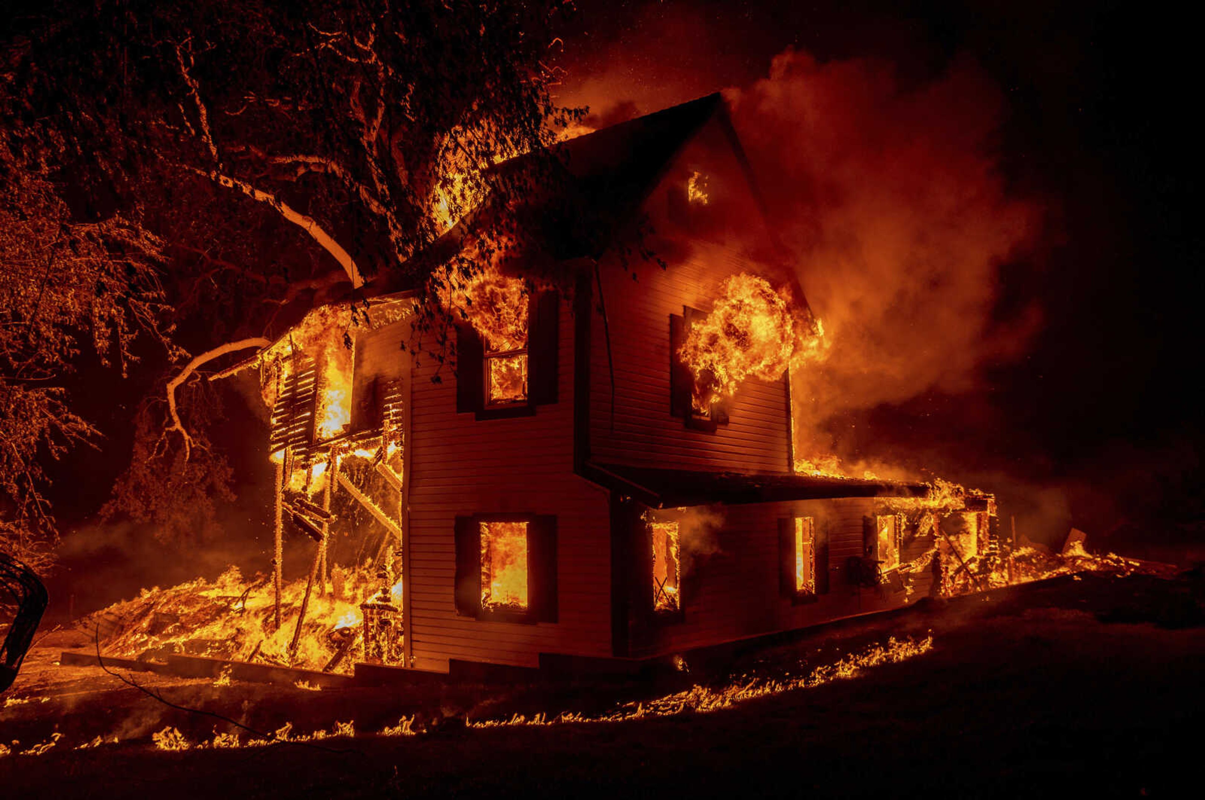 A home burns as the Dixie fire jumps Highway 395 on Aug. 16, 2021, south of Janesville, California. Two insurance industry giants have pulled out of the California marketplace, saying that wildfire risk and the soaring cost of construction prompted them to stop writing new policies in the nation's most populous state.