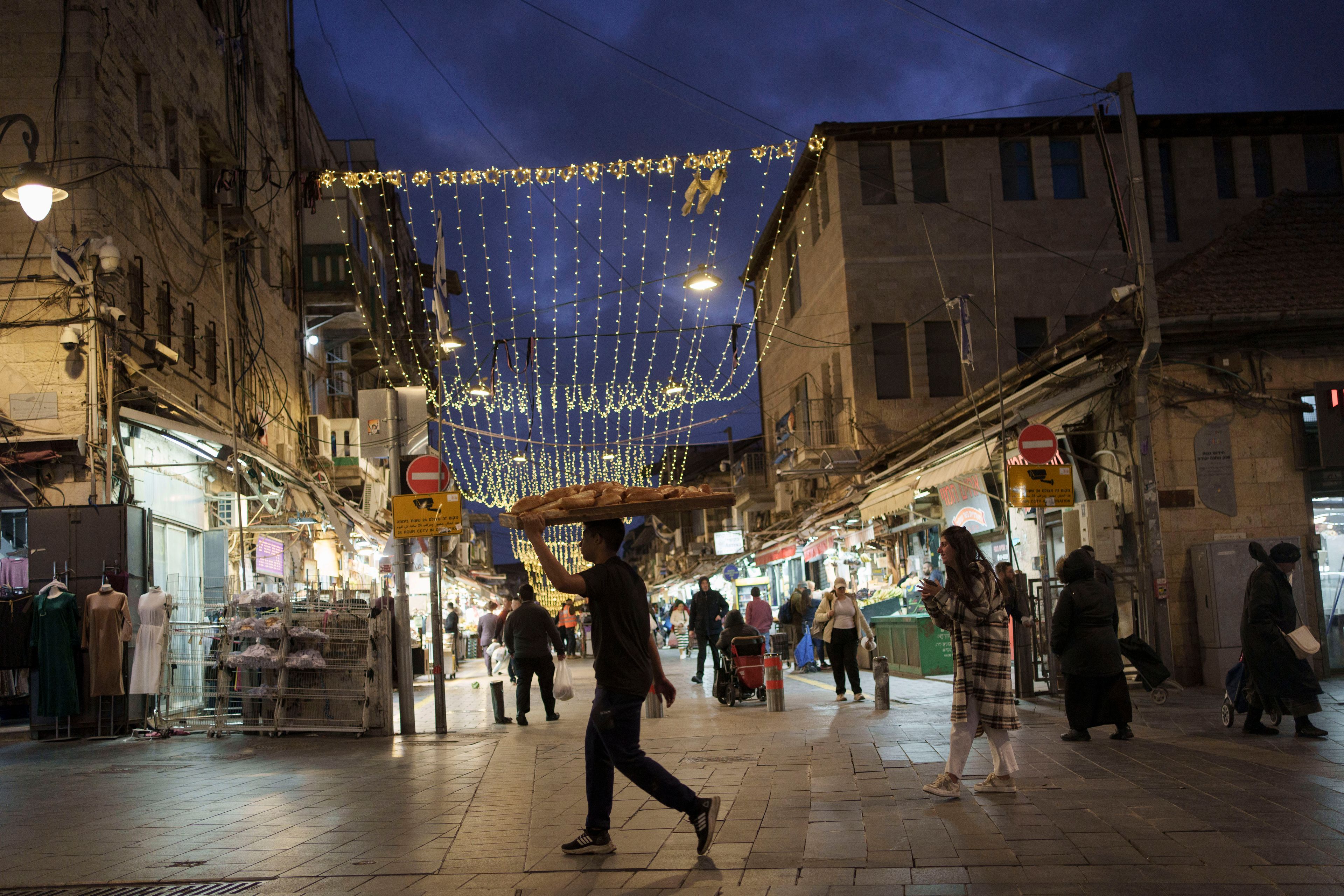 FILE - A man carry breads on a board over his head at the Mahane Yehuda market in Jerusalem, on March 6, 2024. (AP Photo/Leo Correa, File)