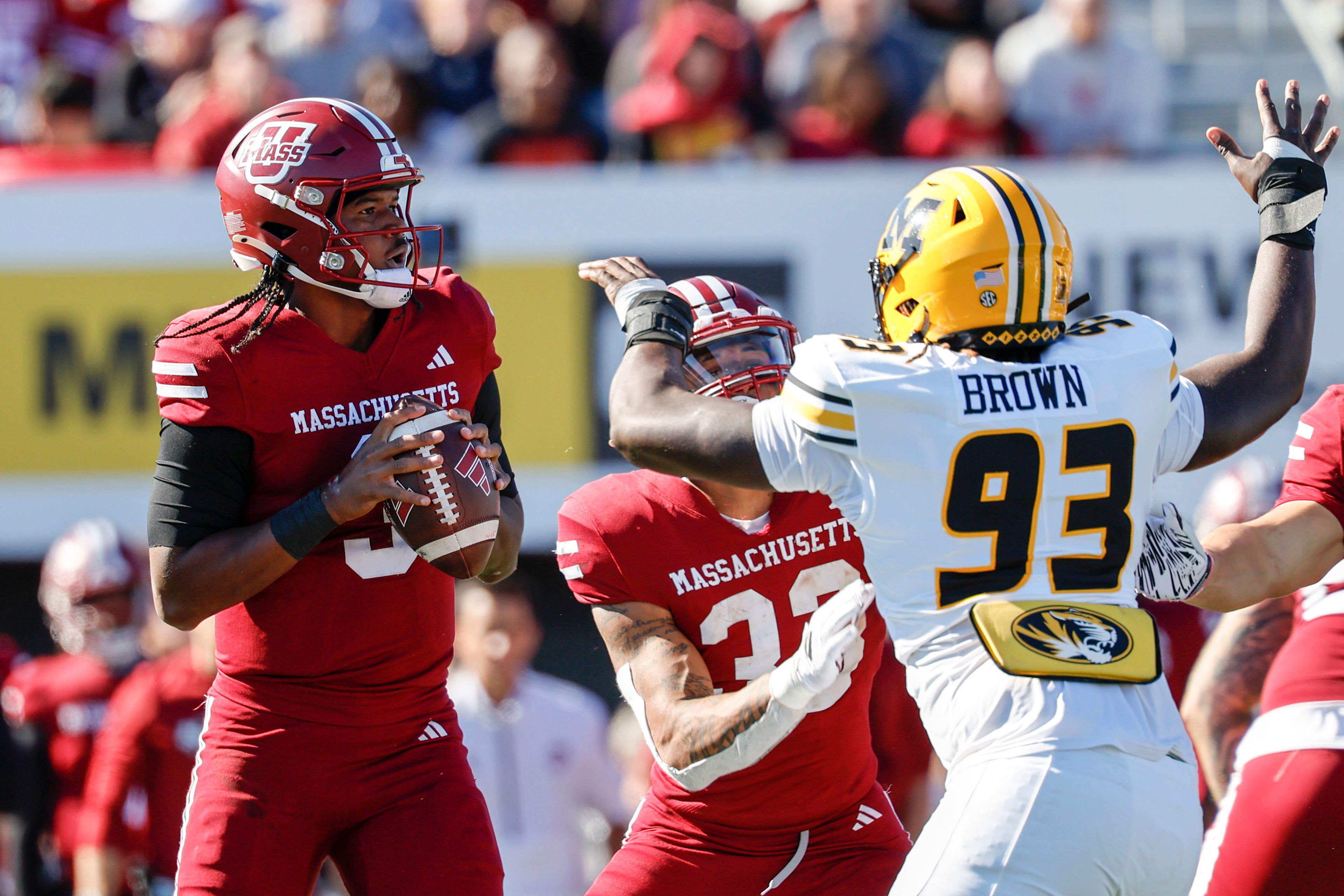 Massachusetts quarterback Taisun Phommachanh (3) prepares to make a pass while running back CJ Hester (33) keeps Missouri defensive end Jaylen Brown (93) away during the second half of an NCAA football game on Saturday, Oct. 12, 2024, in Amherst, Mass. (AP Photo/Greg M. Cooper)