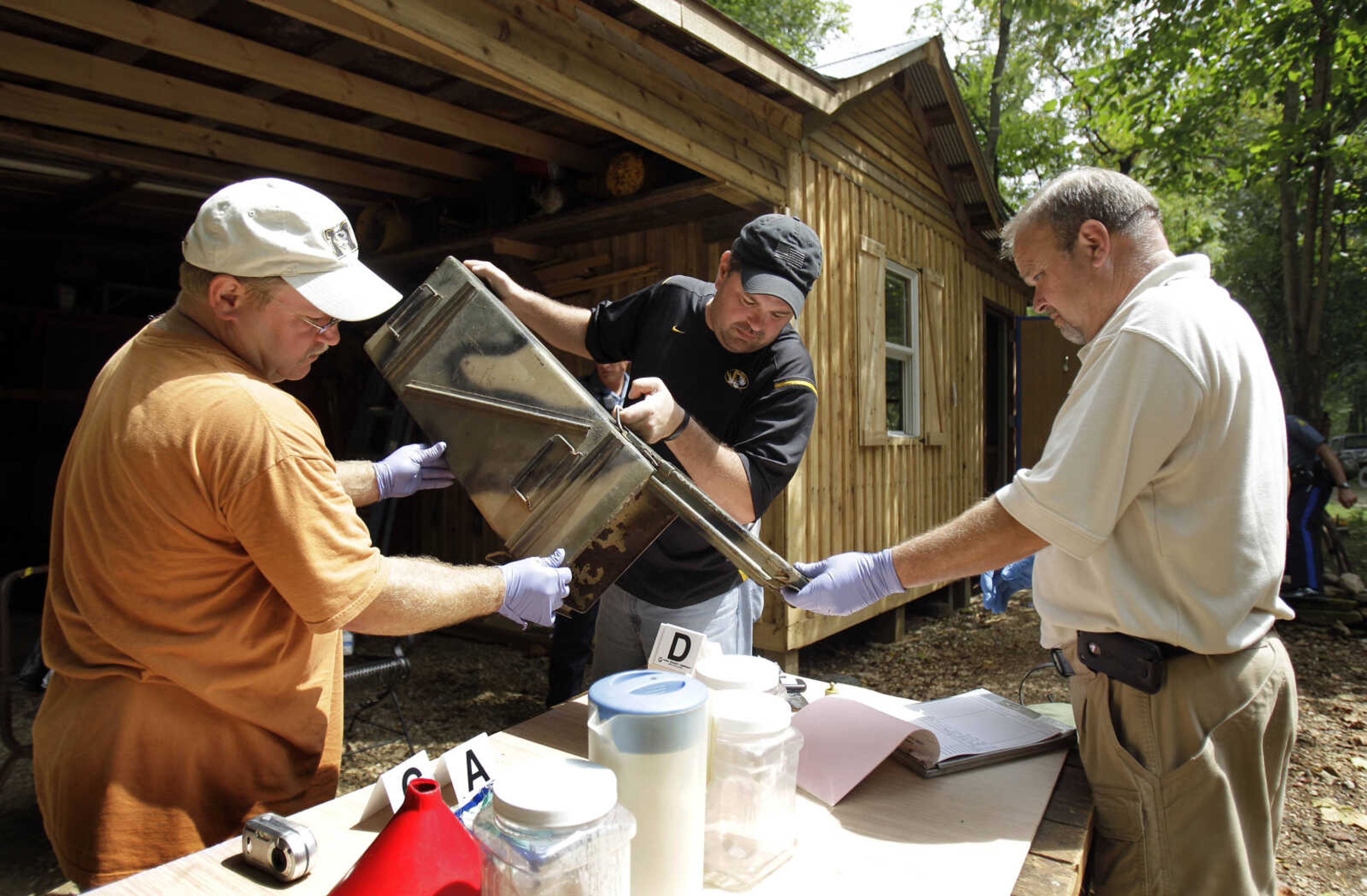 FILE - In this Sept. 2, 2010 file photo, Franklin County Detective Jason Grellner, center, sorts through evidence with Detective Darryl Balleydier, left, and reserve Officer Mark Holguin during a raid of a suspected meth house in Gerald, Mo. The Missouri State Highway Patrol, citing Drug Enforcement Administration statistics, says Missouri once again leads the nation in meth lab busts and seizures with 1,950 meth lab incidents in 2010. (AP Photo/Jeff Roberson, File)