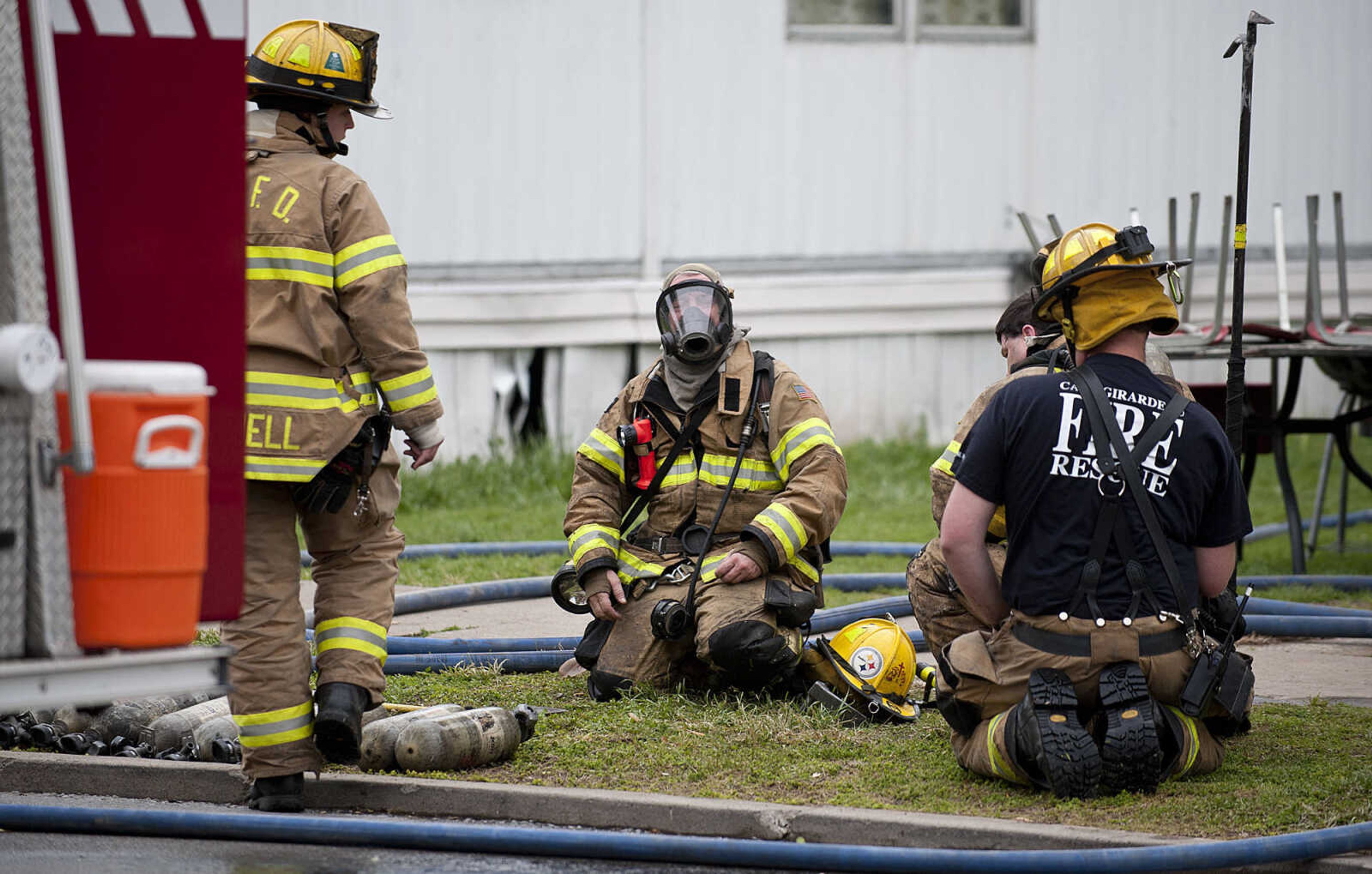 Firefighters take off their gear as the Cape Girardeau battle battle a structure fire at 710 Morgan Oak St., Tuesday, April 29, in Cape Girardeau. A Cape Girardeau Police officer saw the fire and called it in at 1:16 p.m. The building contained two apartments that were home to five people, though no one was home at the time of the fire. The cause of the fire is under investigation.