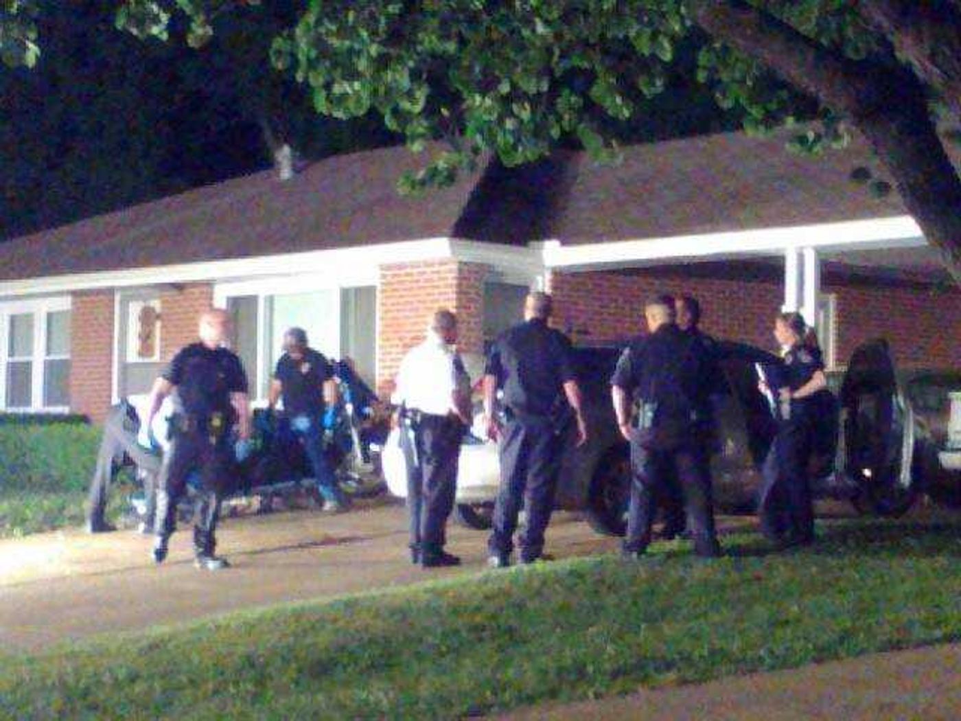 In this cell phone photo, police surround the home at Landgraf Drive, where an apparent shooting left two men dead early Friday morning. (Erin Ragan)