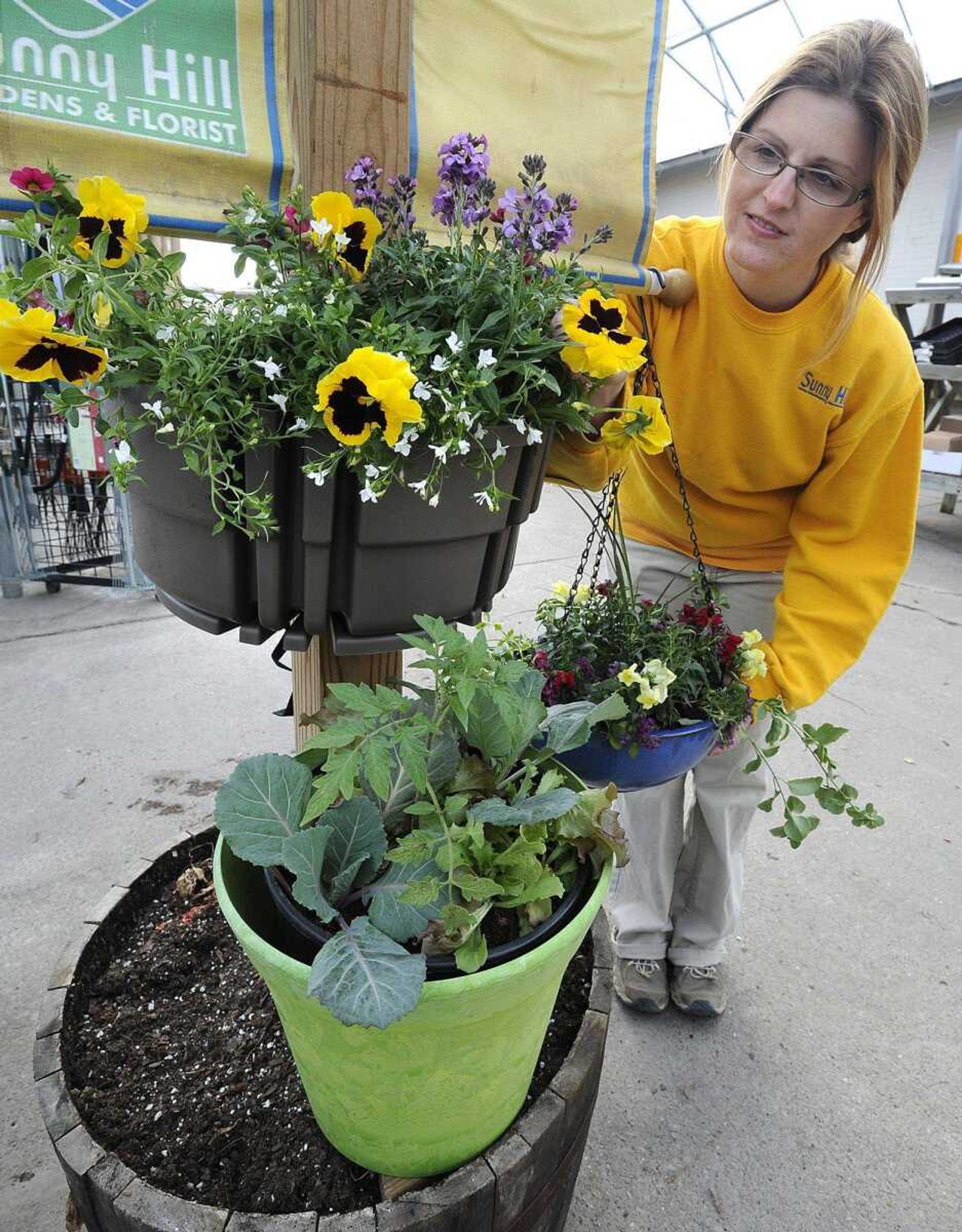 Melissa LaPlant shows three types of gardening containers: a wrap-around with flowers, above; a pot with cabbage, lettuce and tomato; and a hanging container. (Fred Lynch)