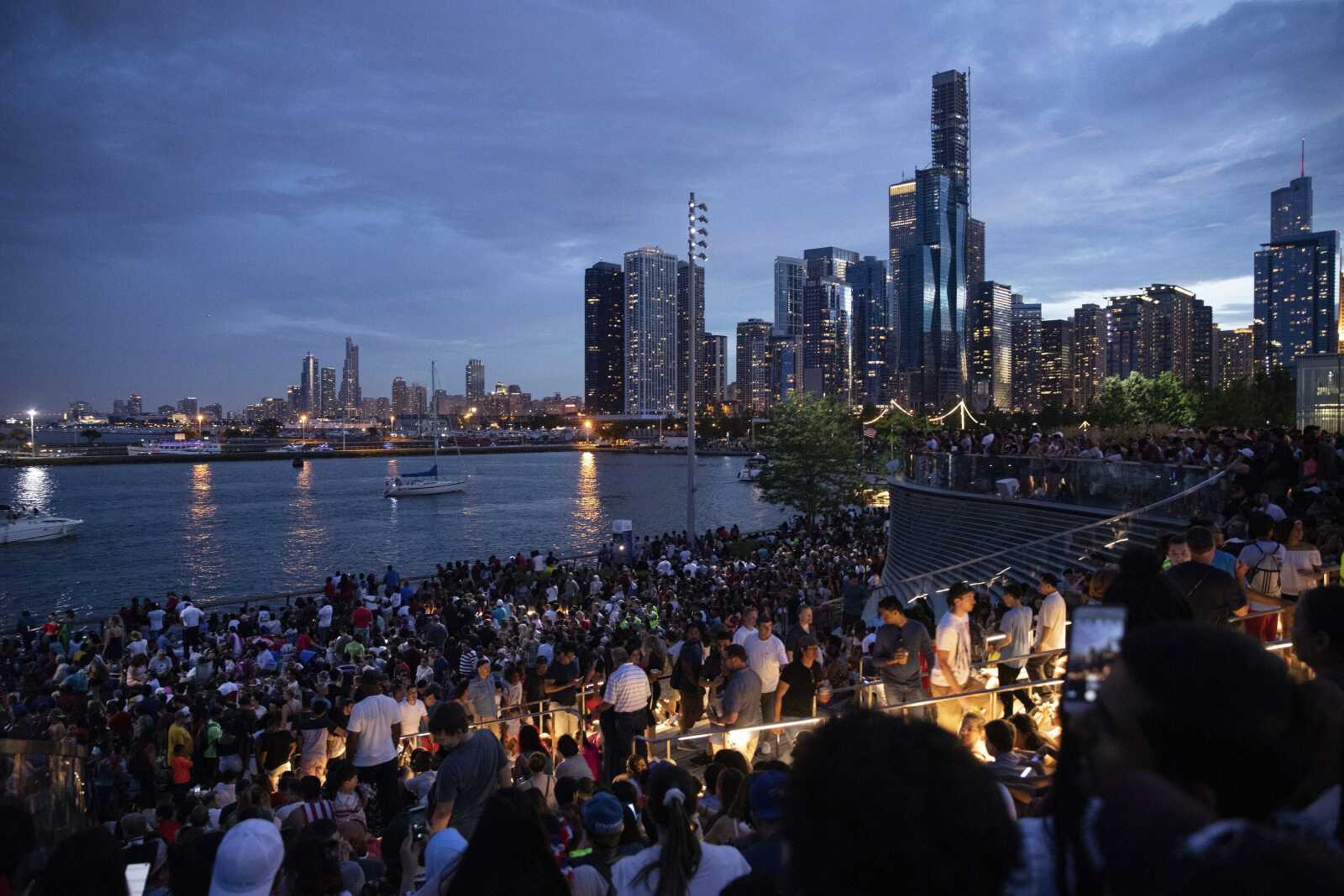 In this Thursday, July 4, 2019 photo, thousands of people gather at Chicago's Navy Pier to celebrate and watch the 4th of July fireworks.  Police said a false report of gunfire set off a stampede that trampled more than a dozen people at Chicago's annual July 4 fireworks display Thursday at Navy Pier, where thousands of revelers had crowded the Lake Michigan shore. (AP Photo/Amr Alfiky)