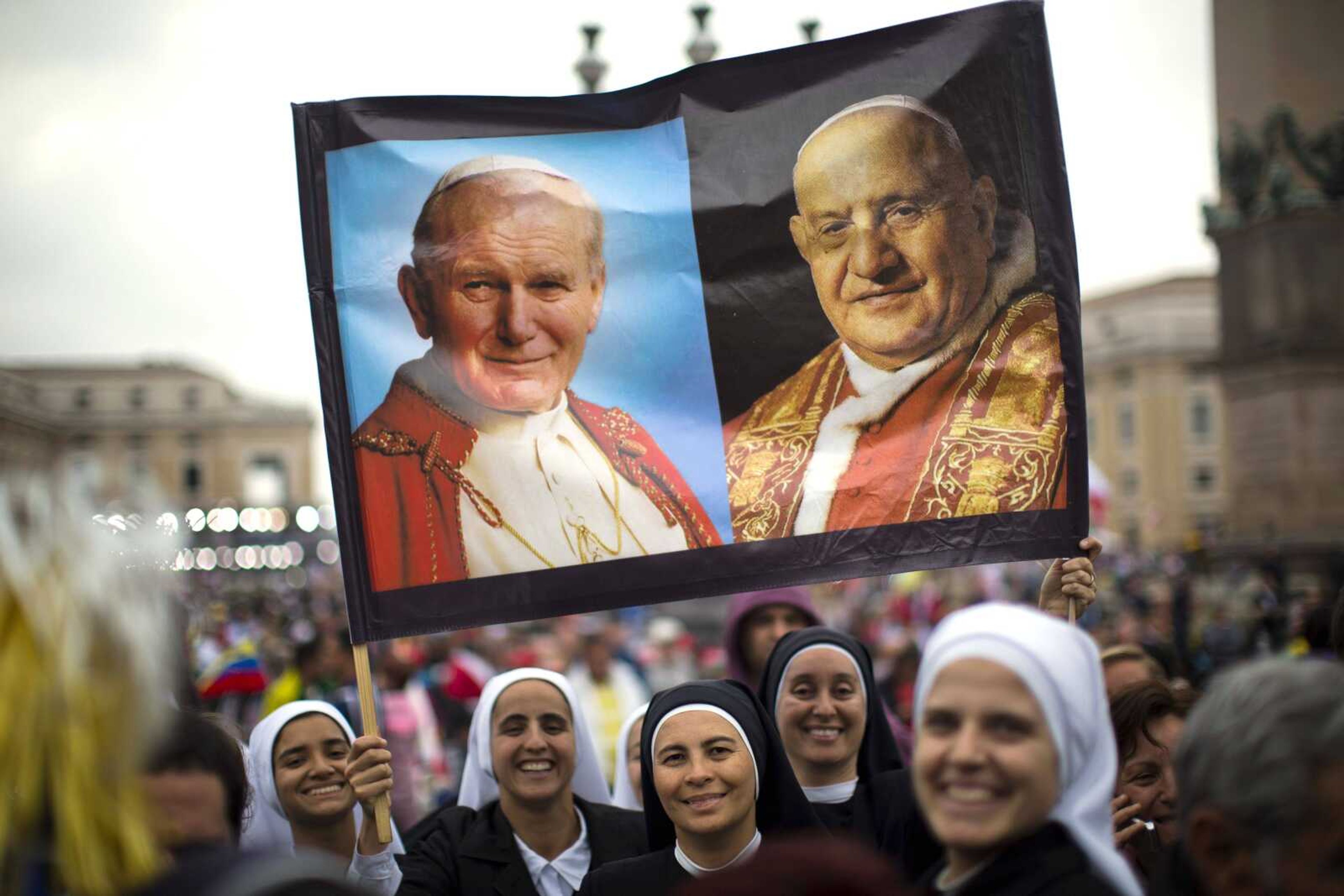 Nuns hold up a poster with portraits of popes John Paul II, left, and John XXIII in St. Peter&#8217;s Square on Sunday at the Vatican. (Emilio Morenatti ~ Associated Press)