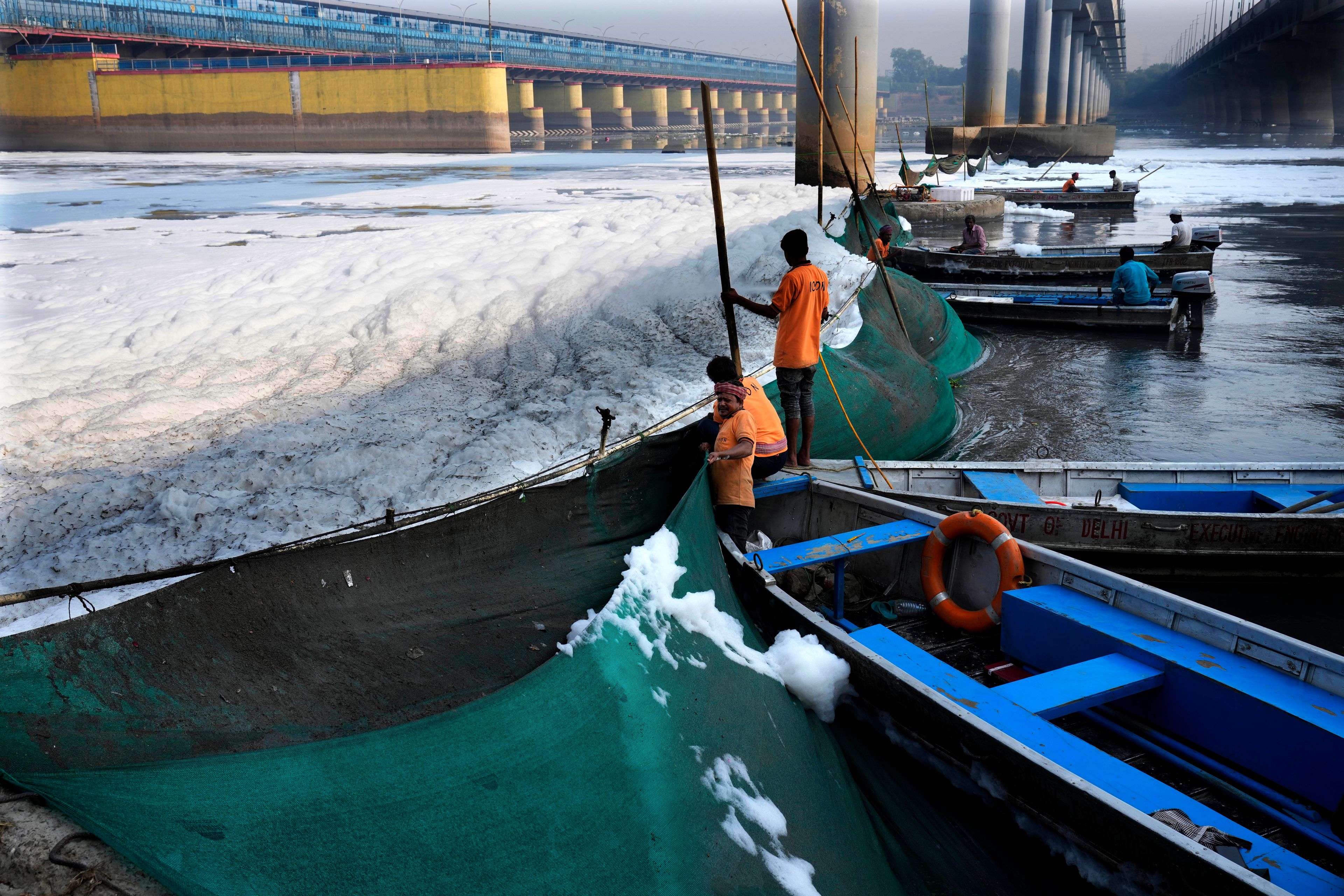 Workers for the Delhi Jal or water board put up a cloth curtain to stop the flow of the toxic foams floating in the river Yamuna in New Delhi, India, Tuesday, Oct. 29, 2024. (AP Photo/Manish Swarup)