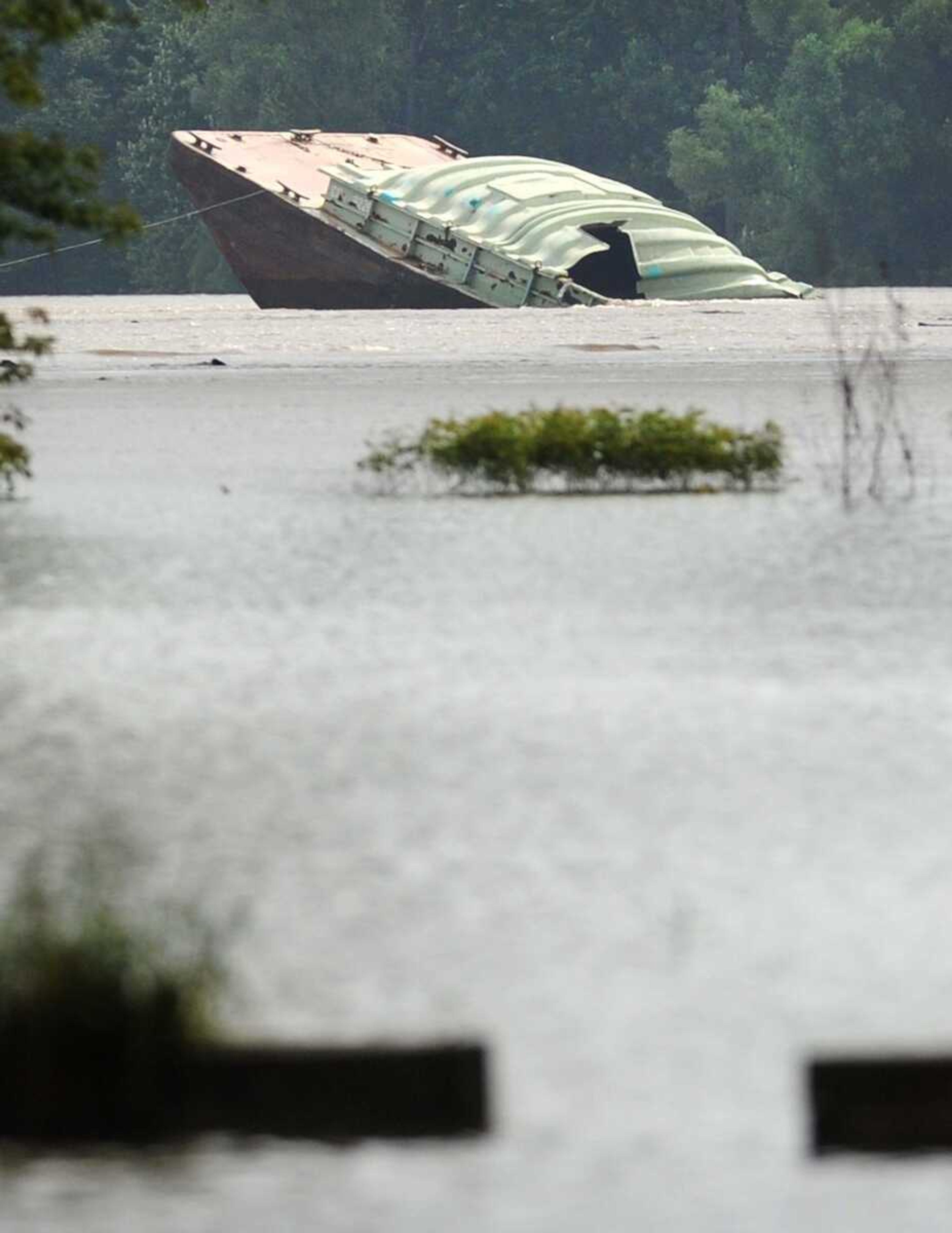 A portion of a sunken barge peeks out from the swollen Mississippi River just south of the Thebes, Illinois, railroad bridge Monday. (Laura Simon)