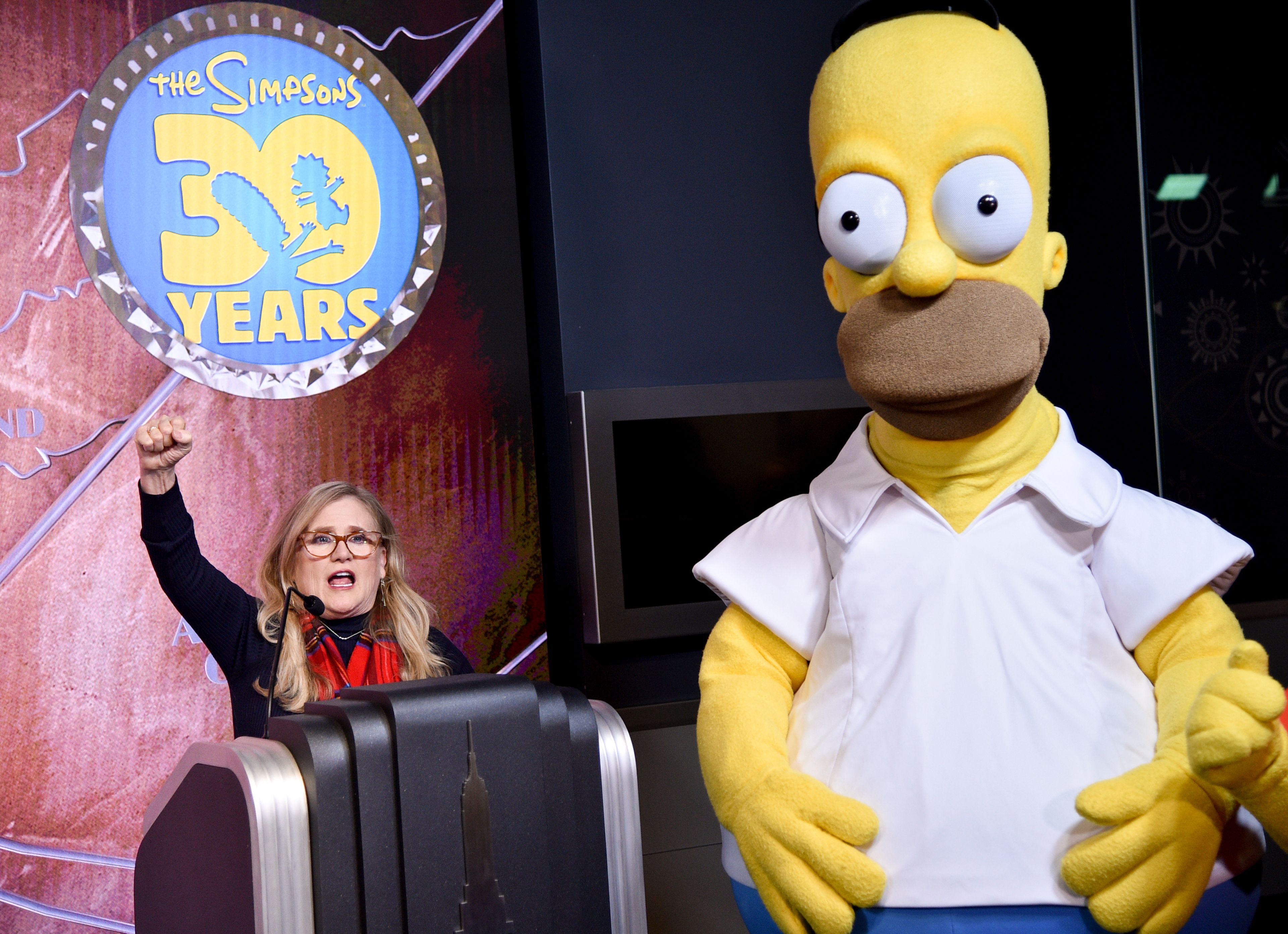 FILE - Nancy Cartwright, who voices the character Bart Simpson, left, appears with costumed character Homer Simpson during Fox's "The Simpsons" 30th anniversary celebration at the Empire State Building on Monday, Dec. 17, 2018, in New York. (Photo by Evan Agostini/Invision/AP, File)