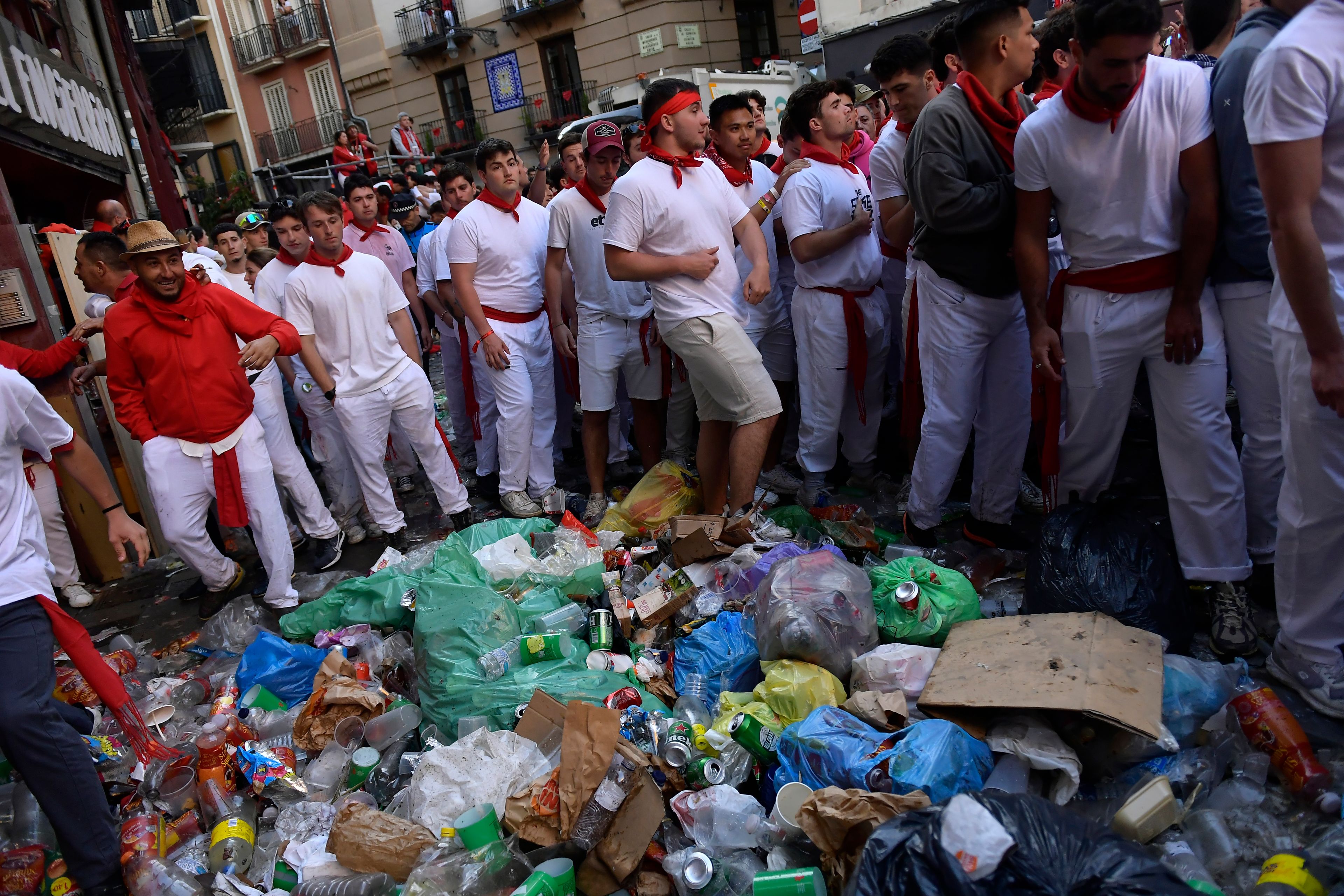 FILE- Revelers stand near a pile of garbage before a bullrun with bulls from La Palmosilla ranch during the first day of the running of the bulls at the San Fermín fiestas in Pamplona, Spain, Sunday, July 7, 2024. (AP Photo/Alvaro Barrientos, File)