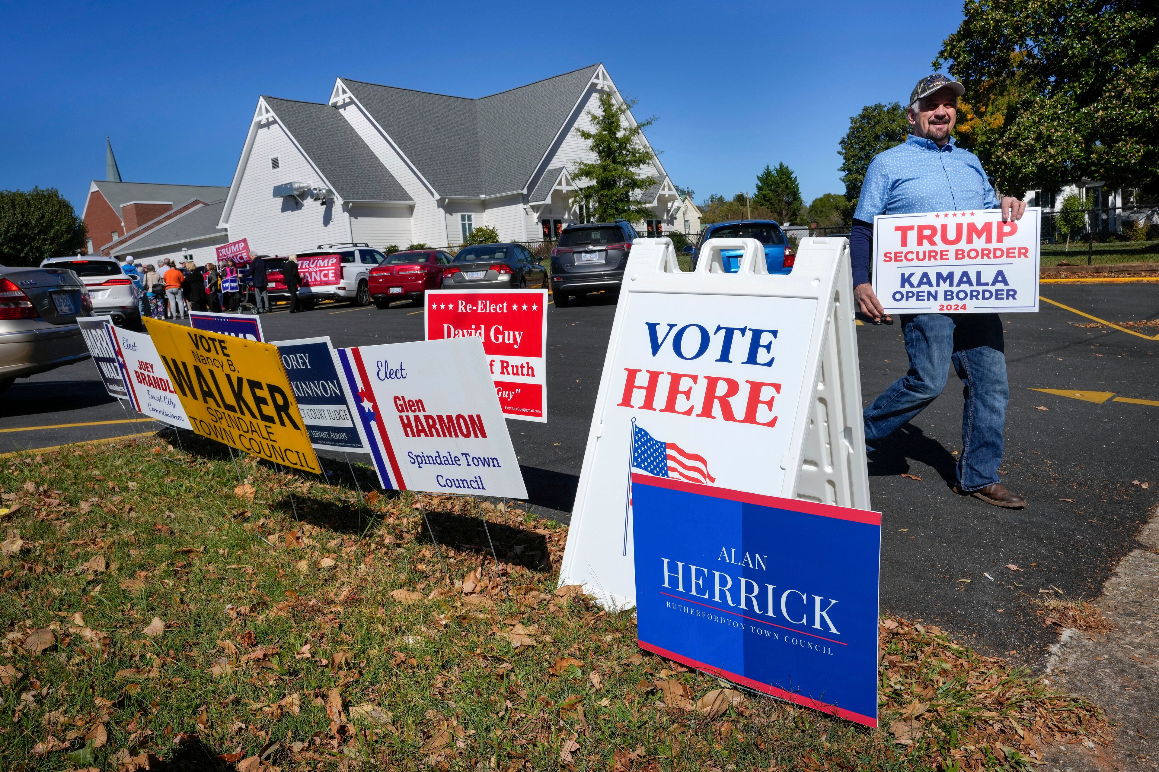 A supporter for former President Trump walks past political signs outside the Rutherford County Annex Building, an early voting site, Thursday, Oct. 17, 2024 in Rutherfordton, N.C. (AP Photo/Kathy Kmonicek)