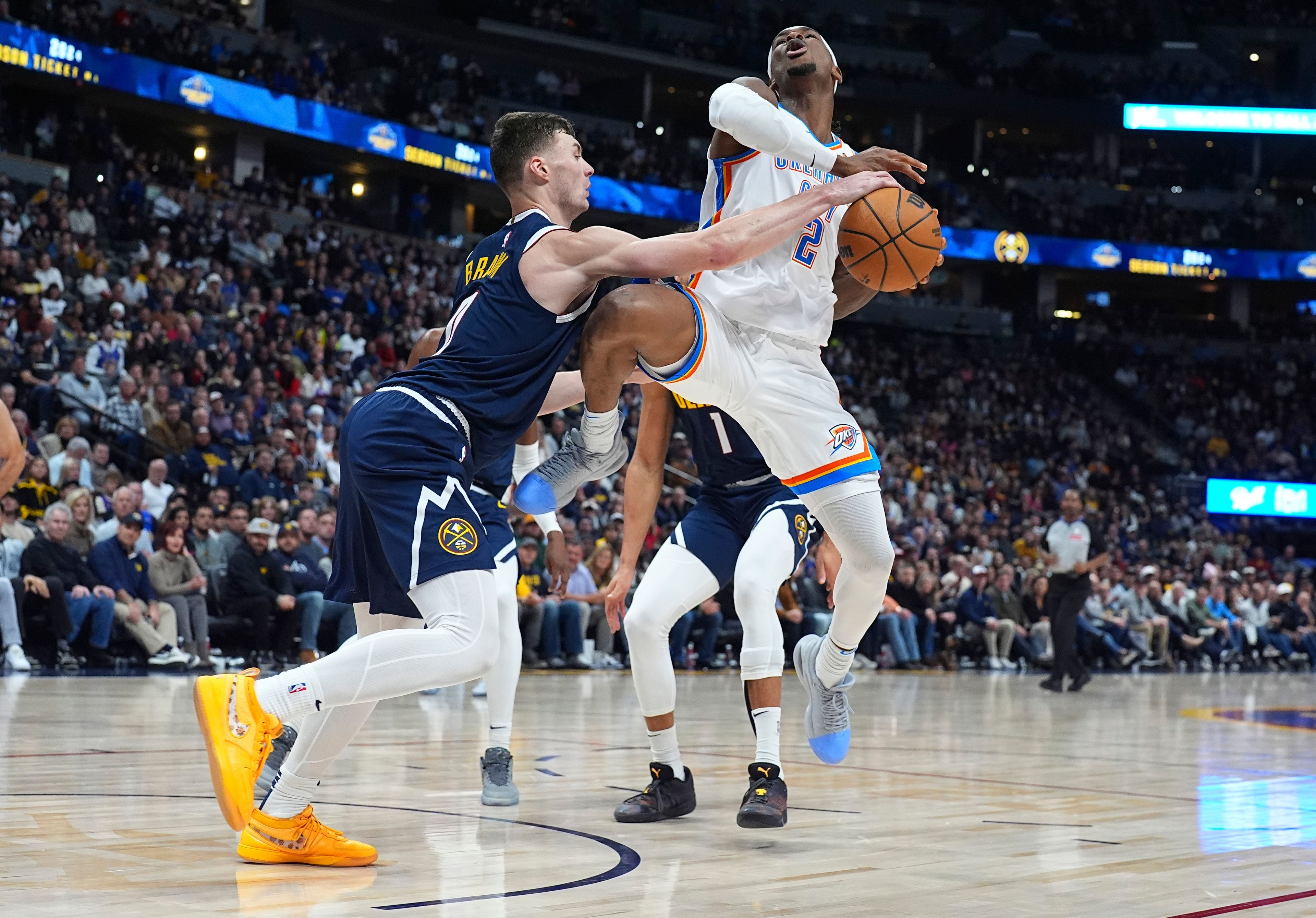 Denver Nuggets guard Christian Braun, left, fouls Oklahoma City Thunder guard Shai Gilgeous-Alexander as he drives the land in the second half of an NBA basketball game Wednesday, Nov. 6, 2024, in Denver. (AP Photo/David Zalubowski)