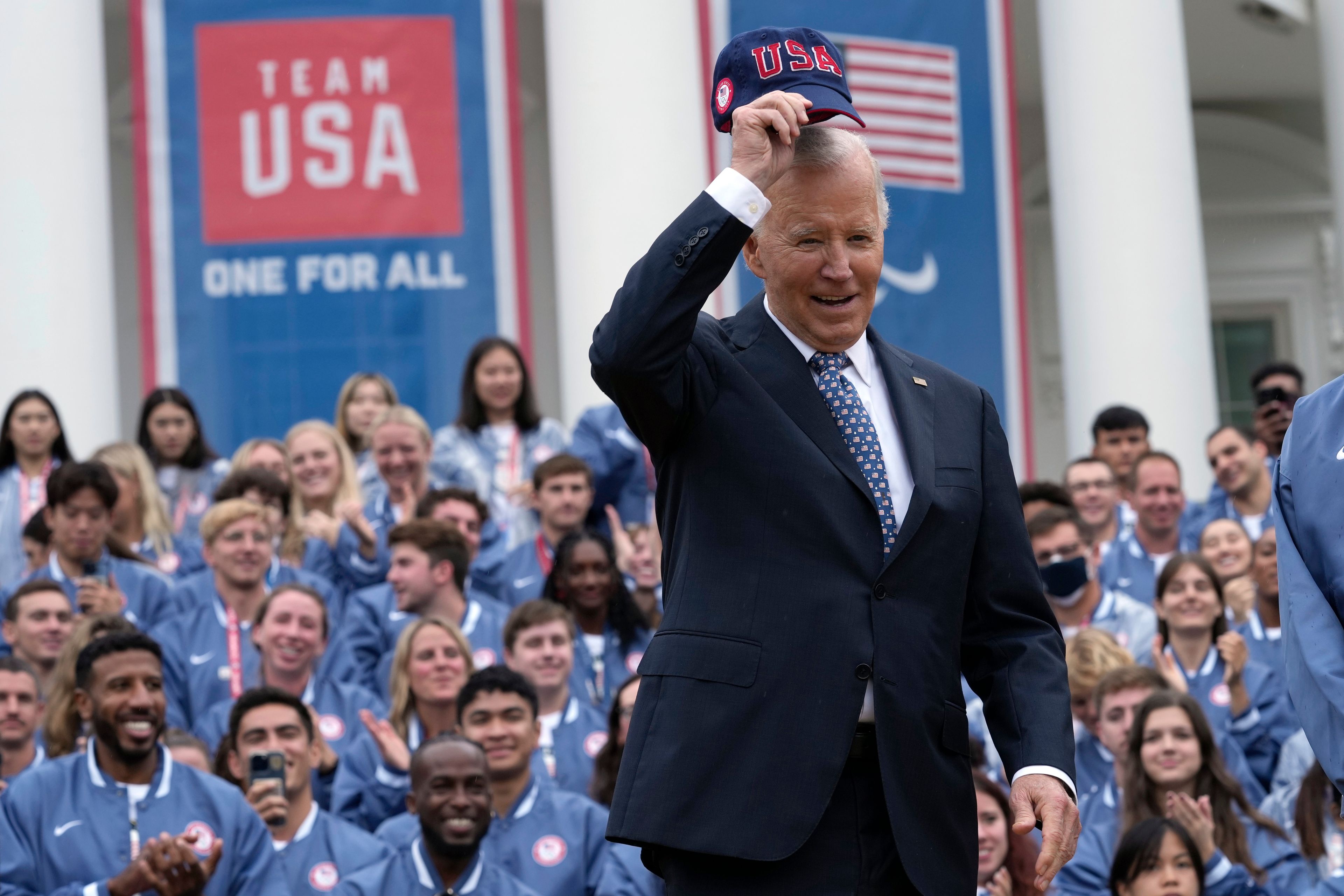 President Joe Biden puts on a hat before he delivers remarks at an event celebrating the 2024 U.S. Olympic and Paralympic teams on the South Lawn of the White House in Washington, Monday, Sept. 30, 2024. (AP Photo/Susan Walsh)