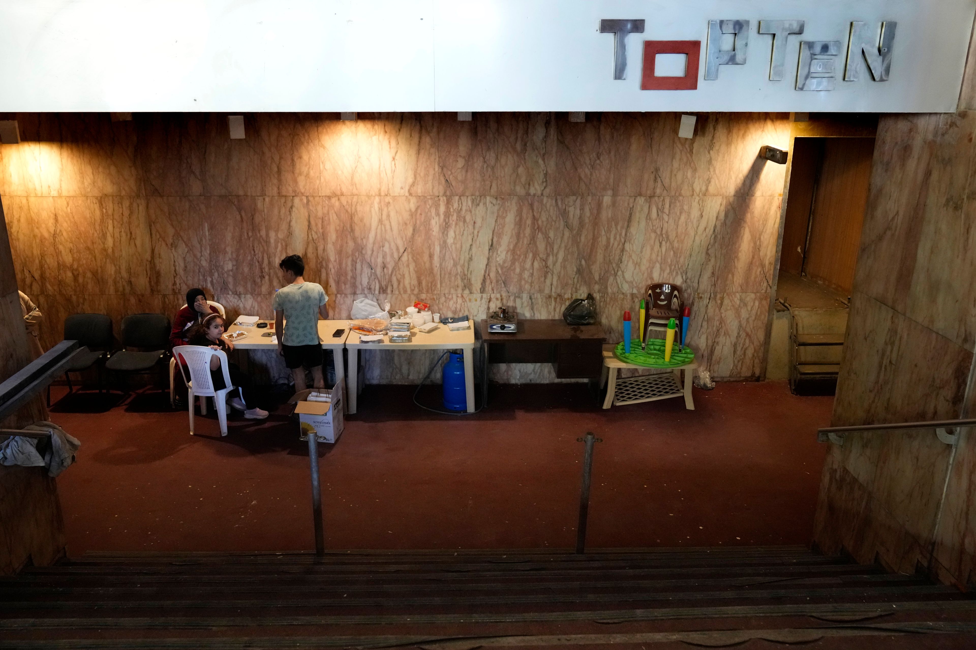 A displaced family, who fled the ongoing Hezbollah-Israel war in south Lebanon, gather inside one of Beirut's oldest and best known movie theatres, Le Colisee, where they are settled now, in Beirut, Lebanon, Tuesday, Oct. 22, 2024. (AP Photo/Hussein Malla)