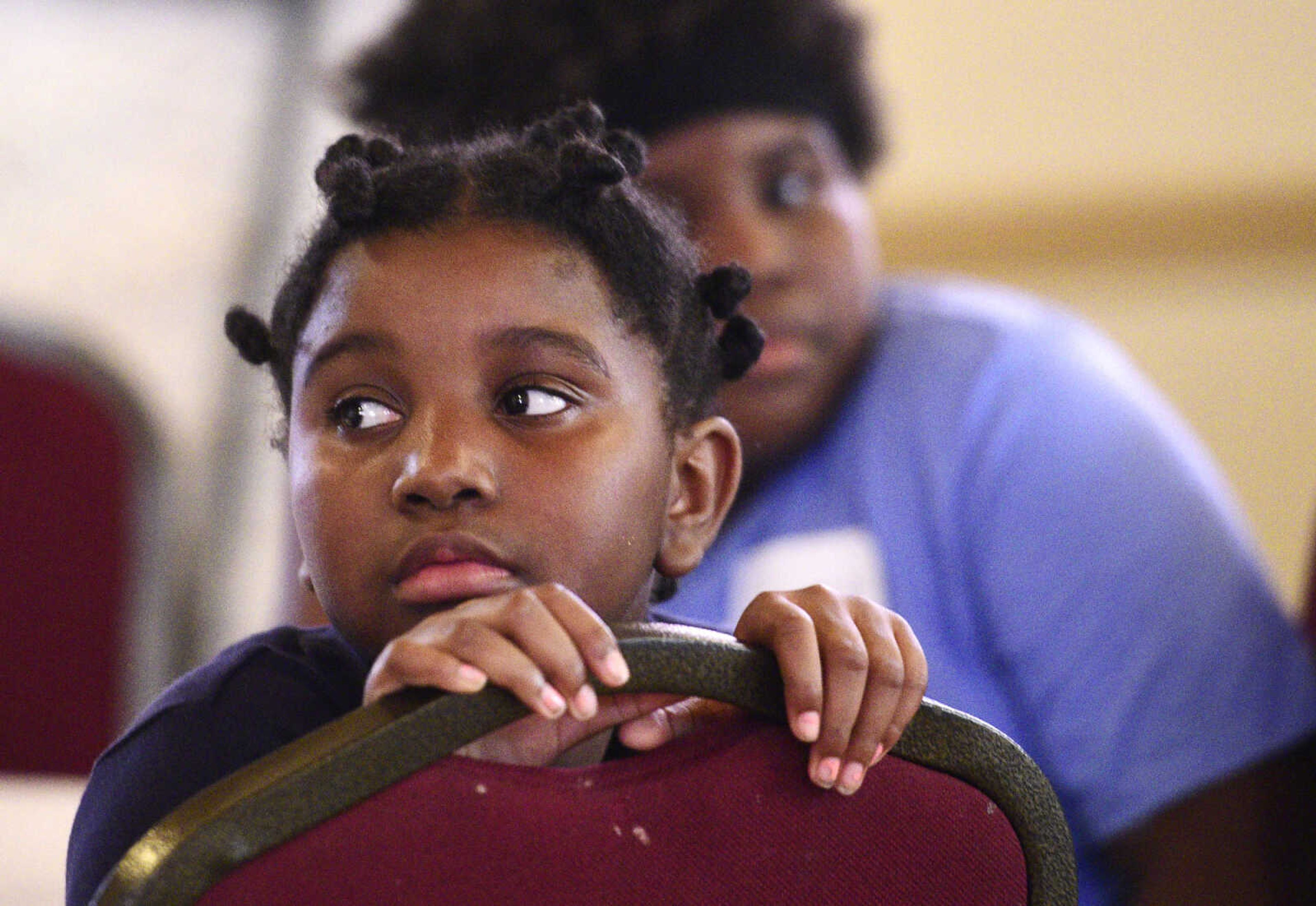 Nala Maney peers over her chair on Monday, Aug. 14, 2017, during the Salvation Army's after school program at The Bridge Outreach Center in Cape Girardeau.