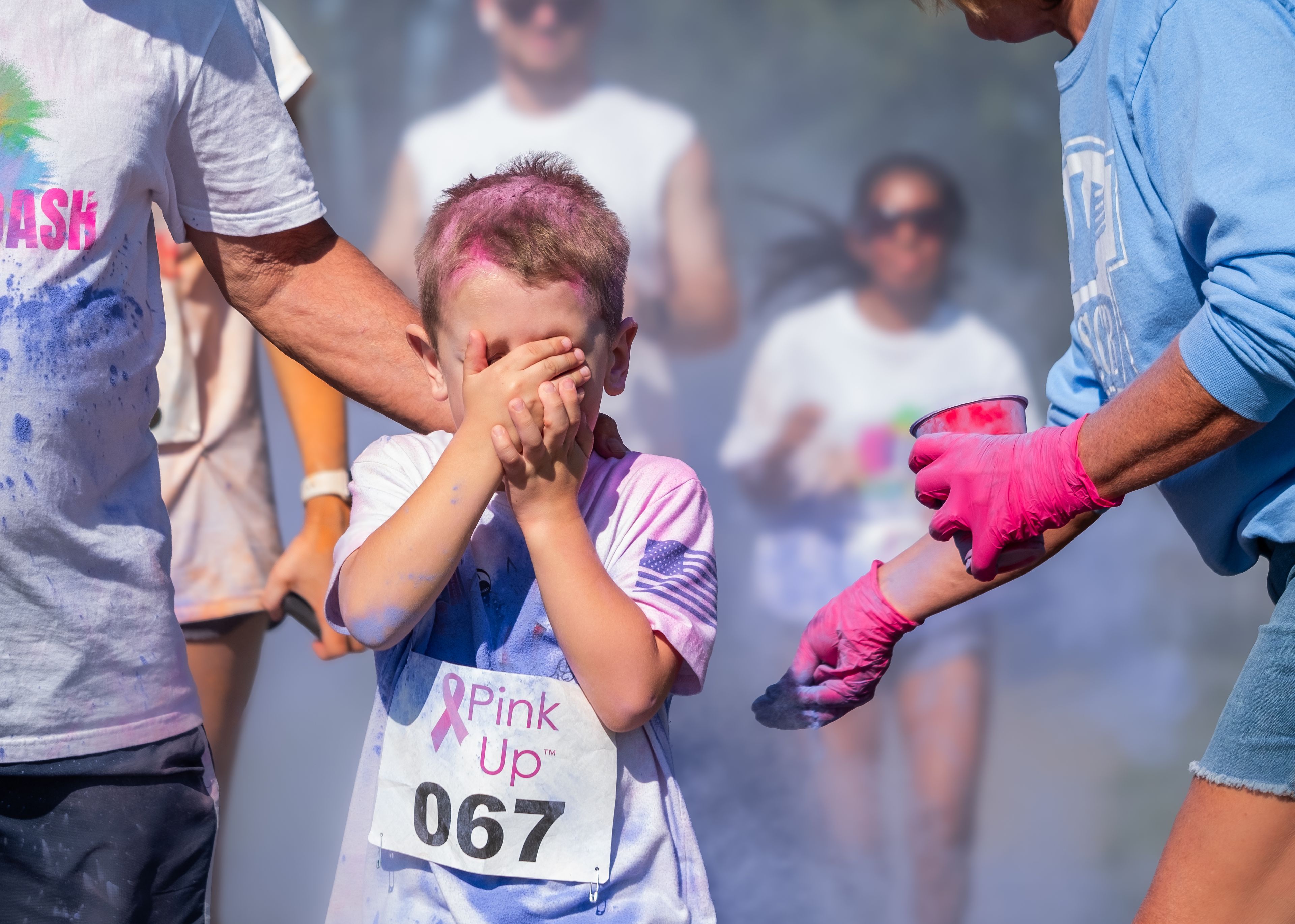 A child shields his eyes from the colorful dust.