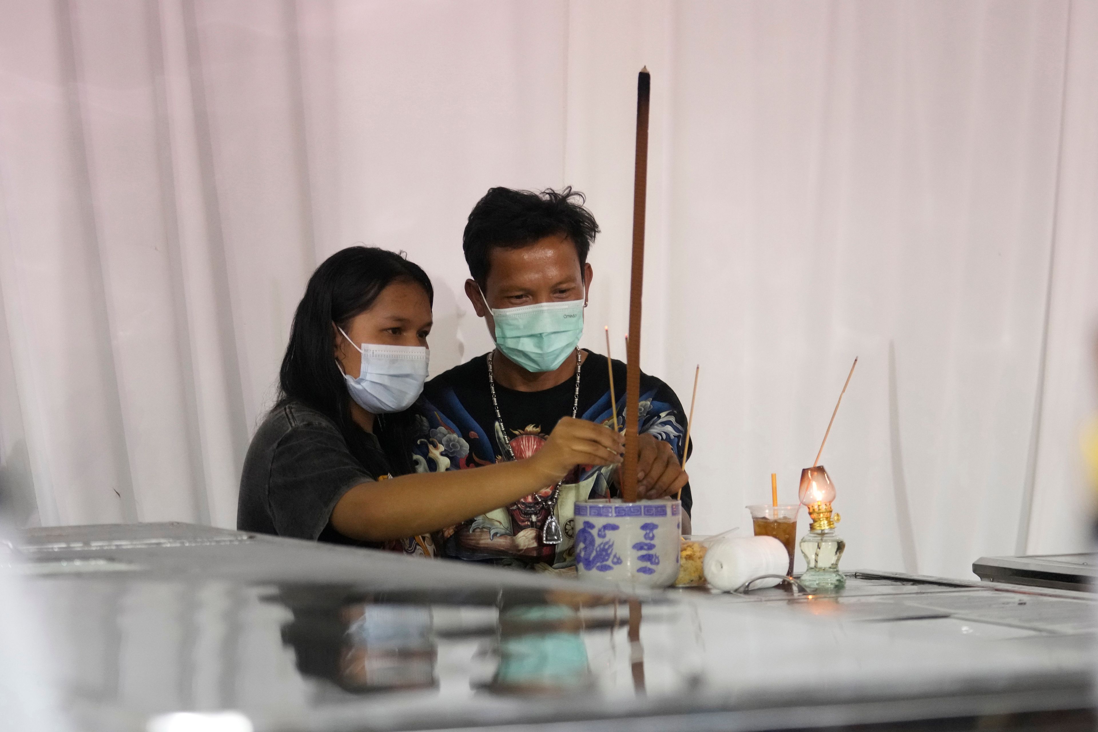 Relatives of the bus fire victims pray at their coffins at Wat Khao Phraya Sangkharam School Lan Sak, Uthai Thani province, Thailand, Wednesday, Oct. 2, 2024. (AP Photo/Sakchai Lalit)