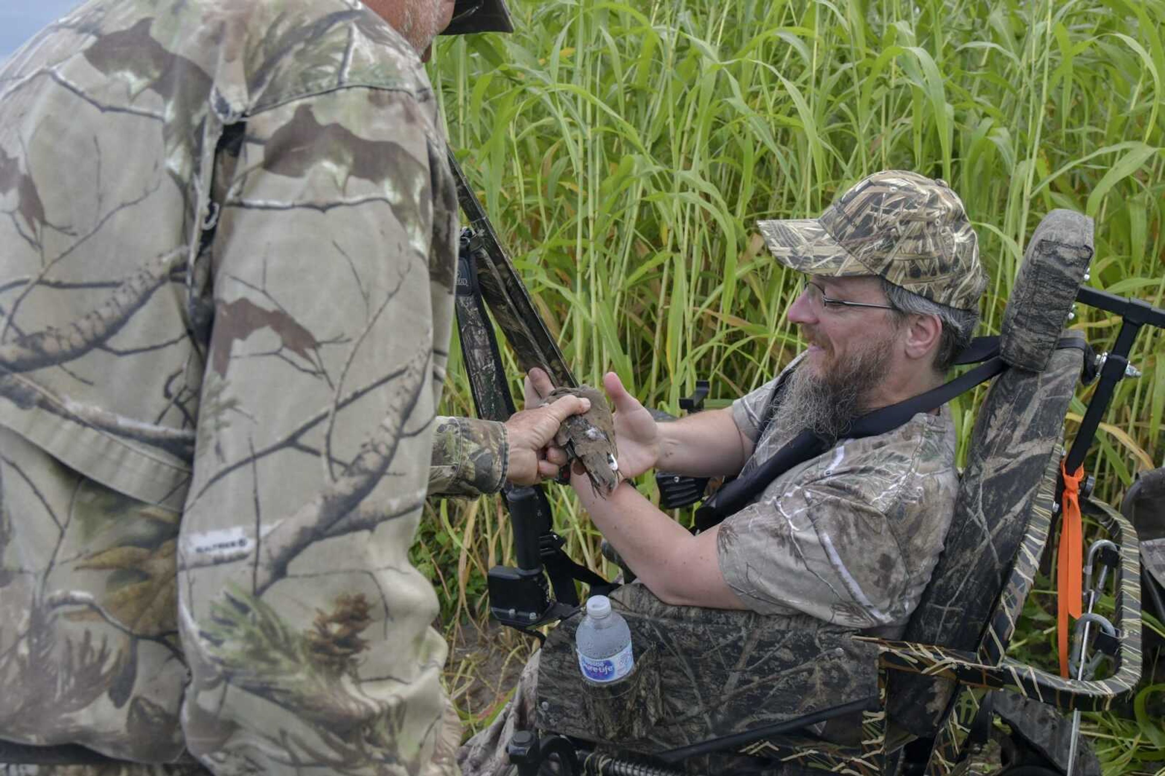 Paul Strickland gives Gabe Glastetter the dove Glastetter successfully shot, which Strickland retrieved, during MDC's Mobility Impaired Dove Hunt at the Ten Mile Pond in East Prairie Wednesday Sept. 1, 2021.