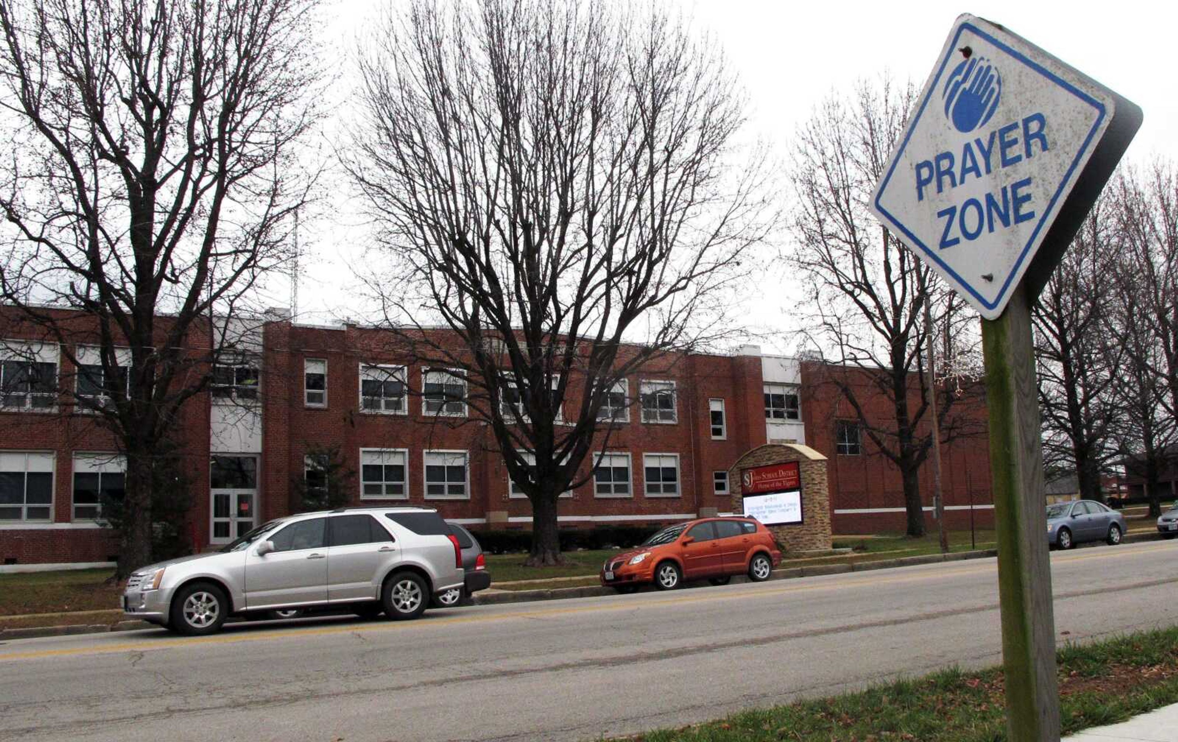 Several cars sit parked Thursday outside John F. Hodge High School in St. James, Mo. The school continues mourning the August 2010 death of 15-year-old marching band member Jessica Brinker in a freeway pileup involving two of the school district&#8217;s buses. Investigators say the driver who began the chain-reaction accident was texting in the moments before the wreck, and federal transportation officials are keying on the accident as reason for their call for all states to ban cellphone use while driving. (Jim Suhr ~ Associated Press)